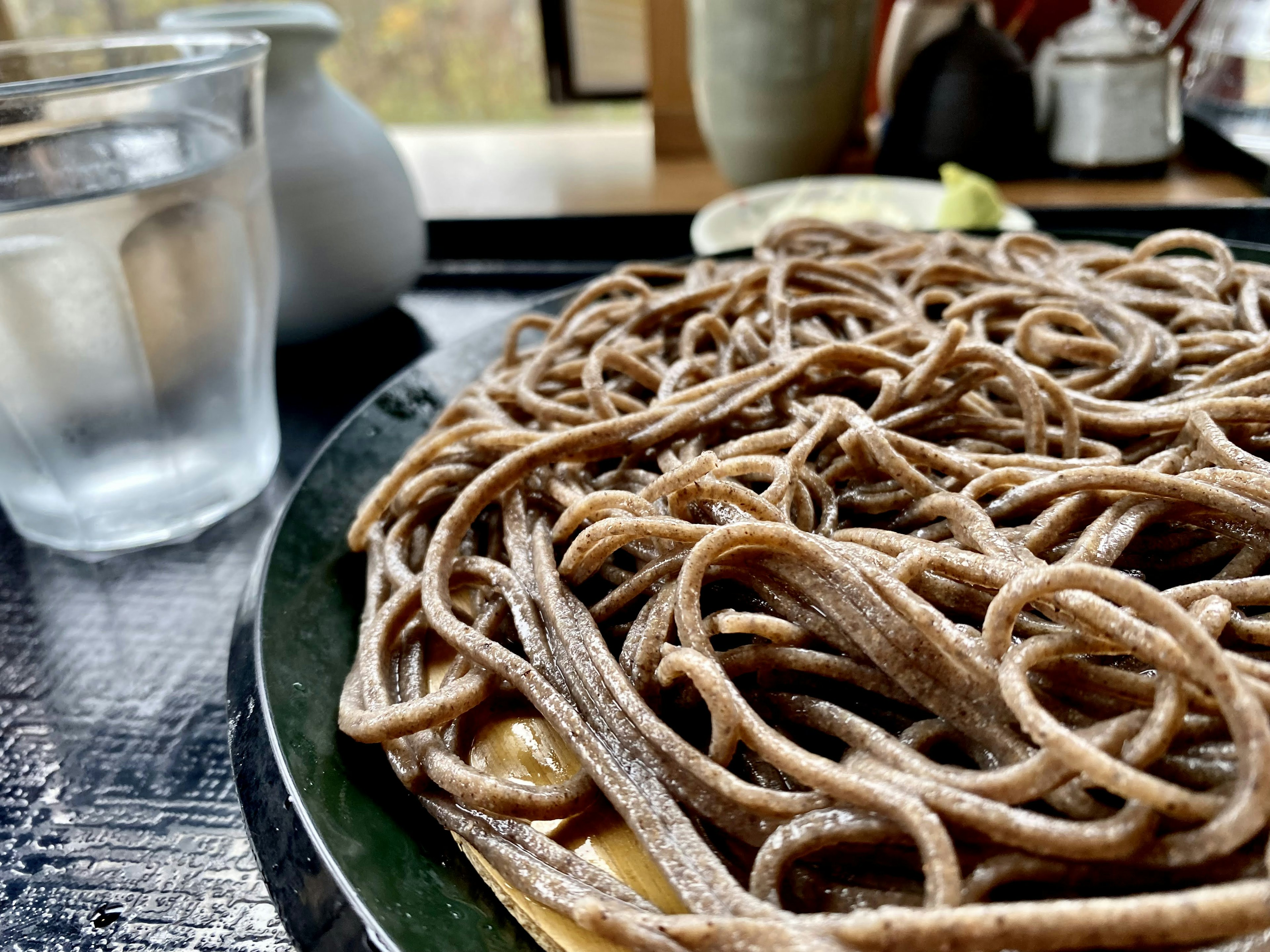 Kedekatan mie soba yang disajikan di piring dengan segelas air