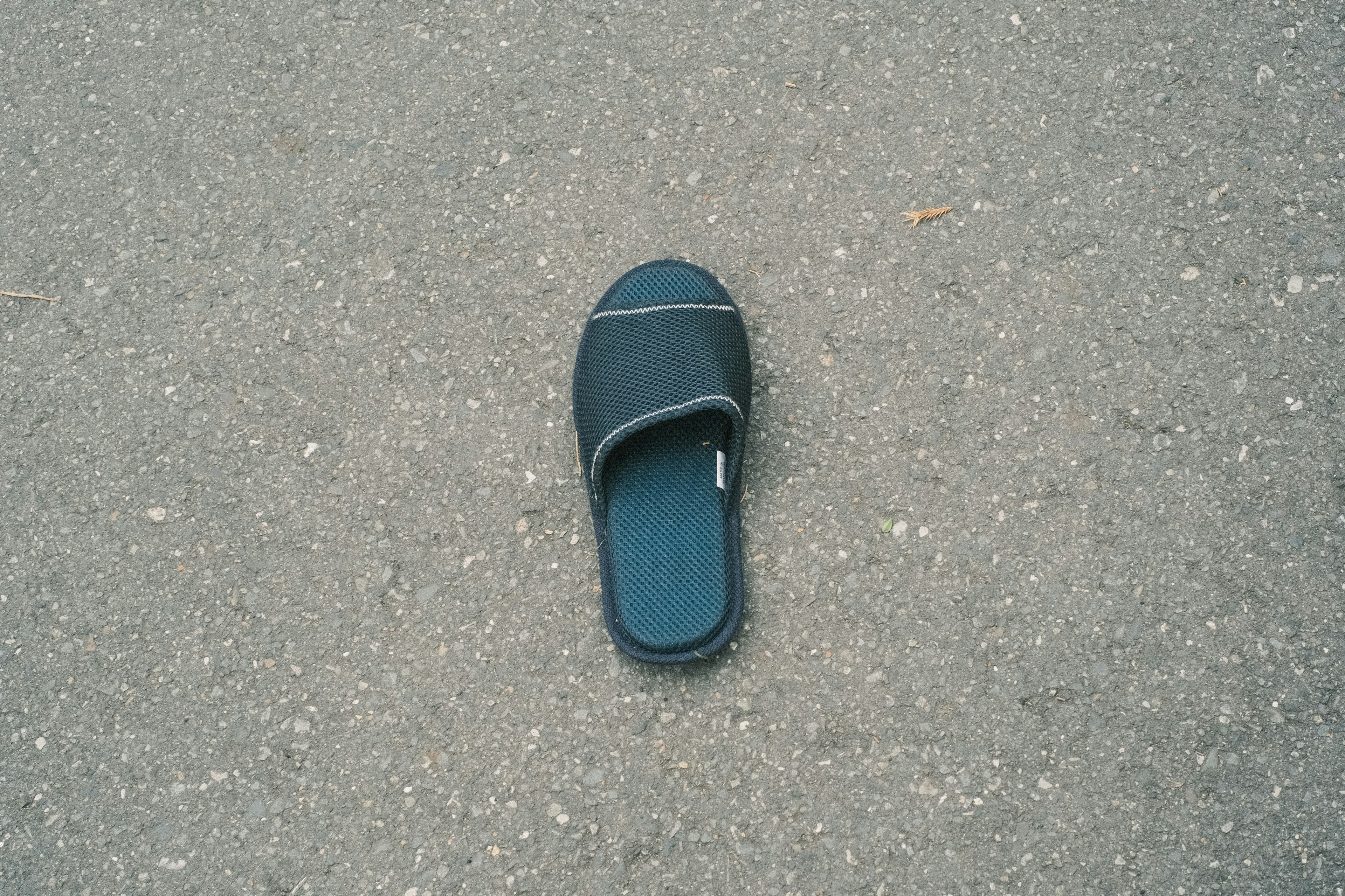 A black slide sandal placed on asphalt pavement