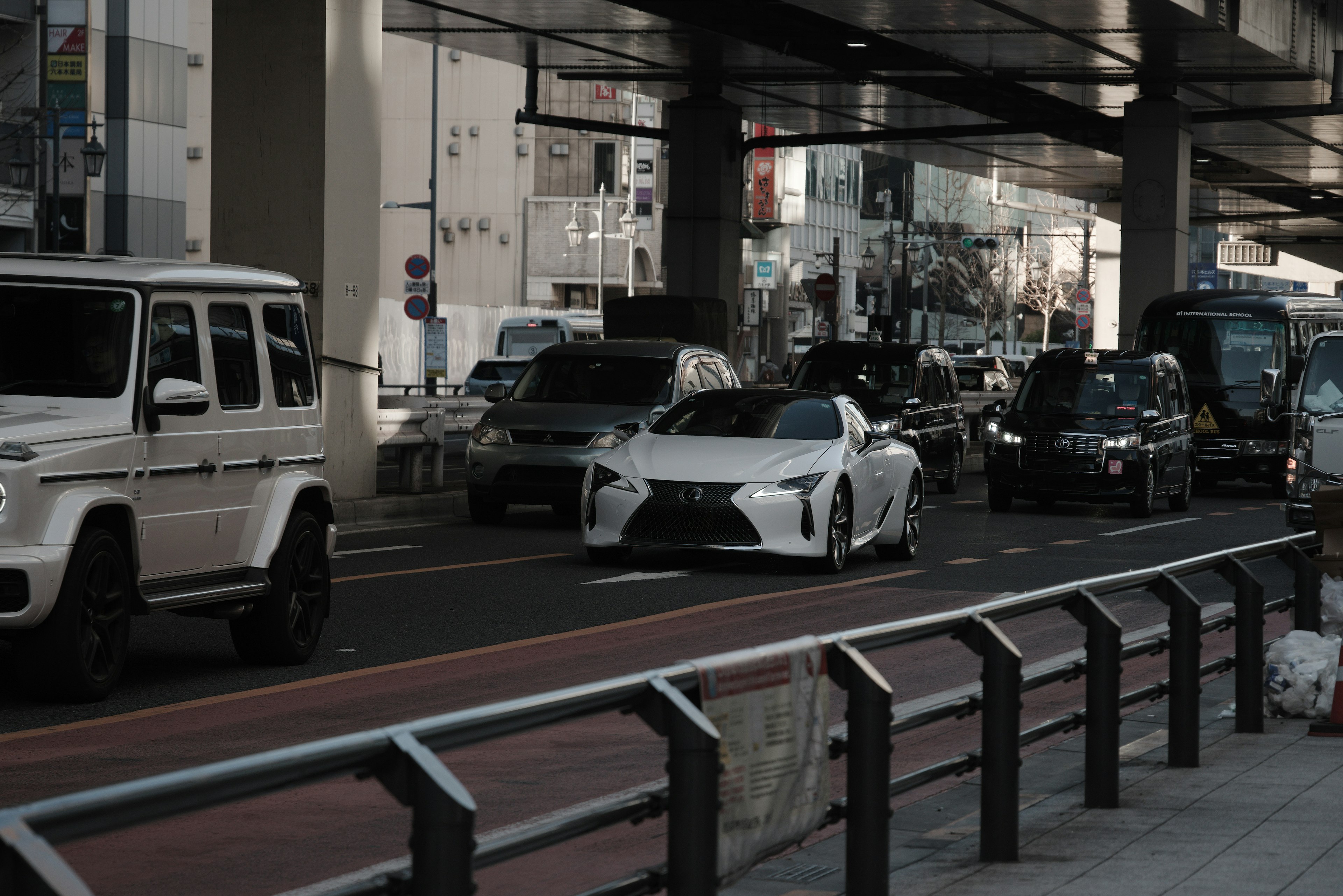 A white sports car driving on an urban street with traffic