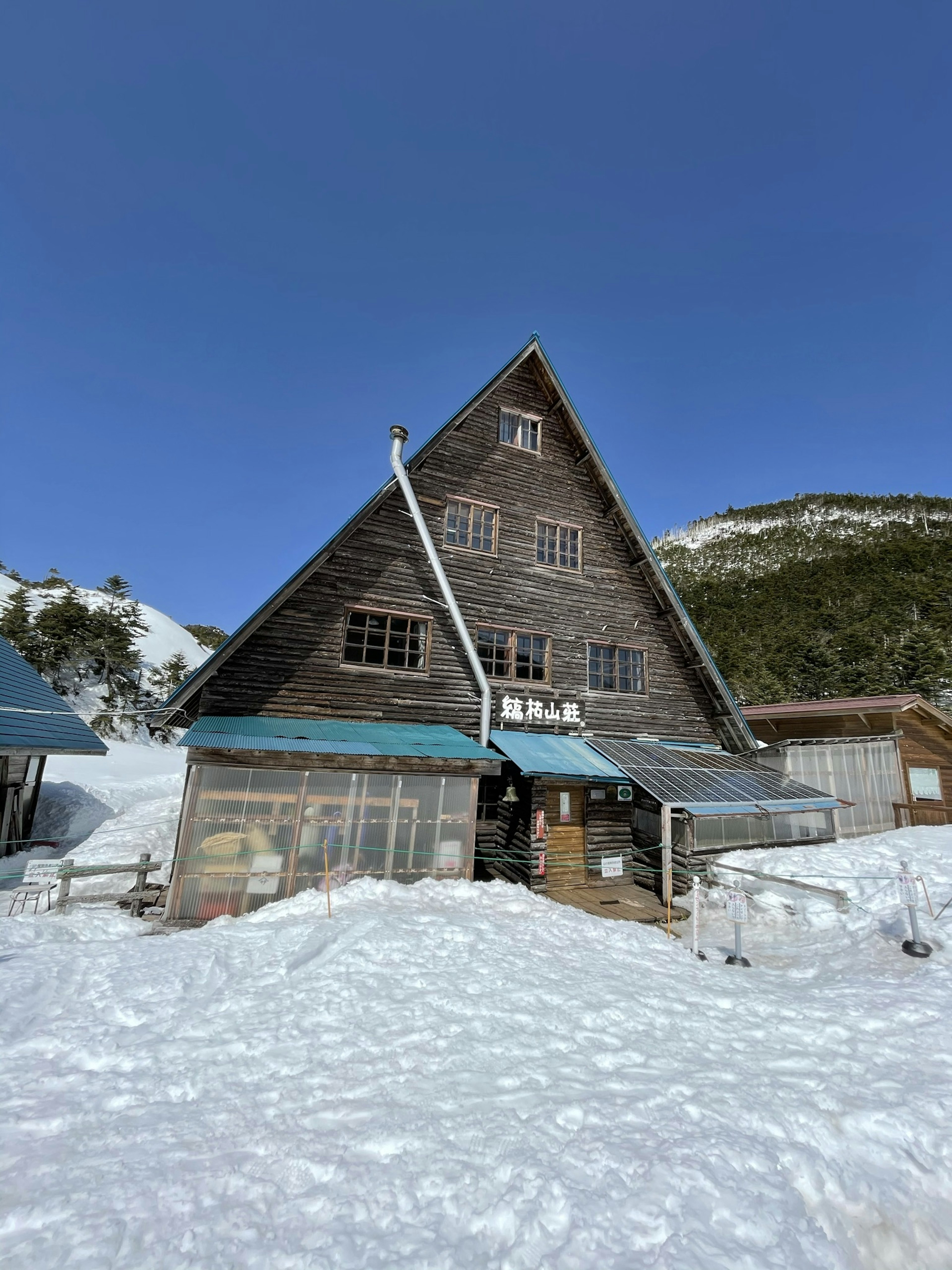 Exterior view of a snow-covered mountain lodge featuring a triangular wooden roof