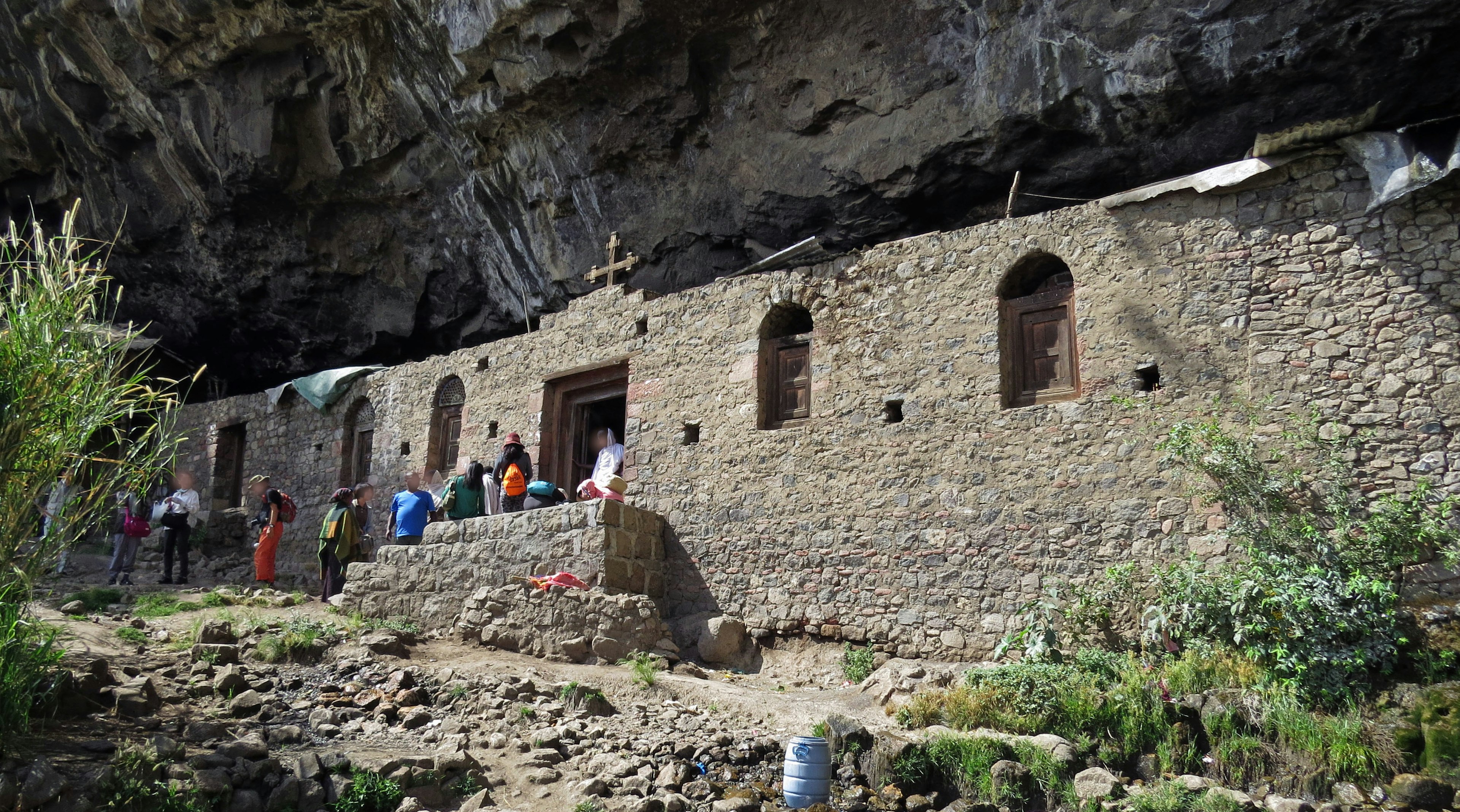 Bâtiment en pierre situé sous une grotte avec des visiteurs