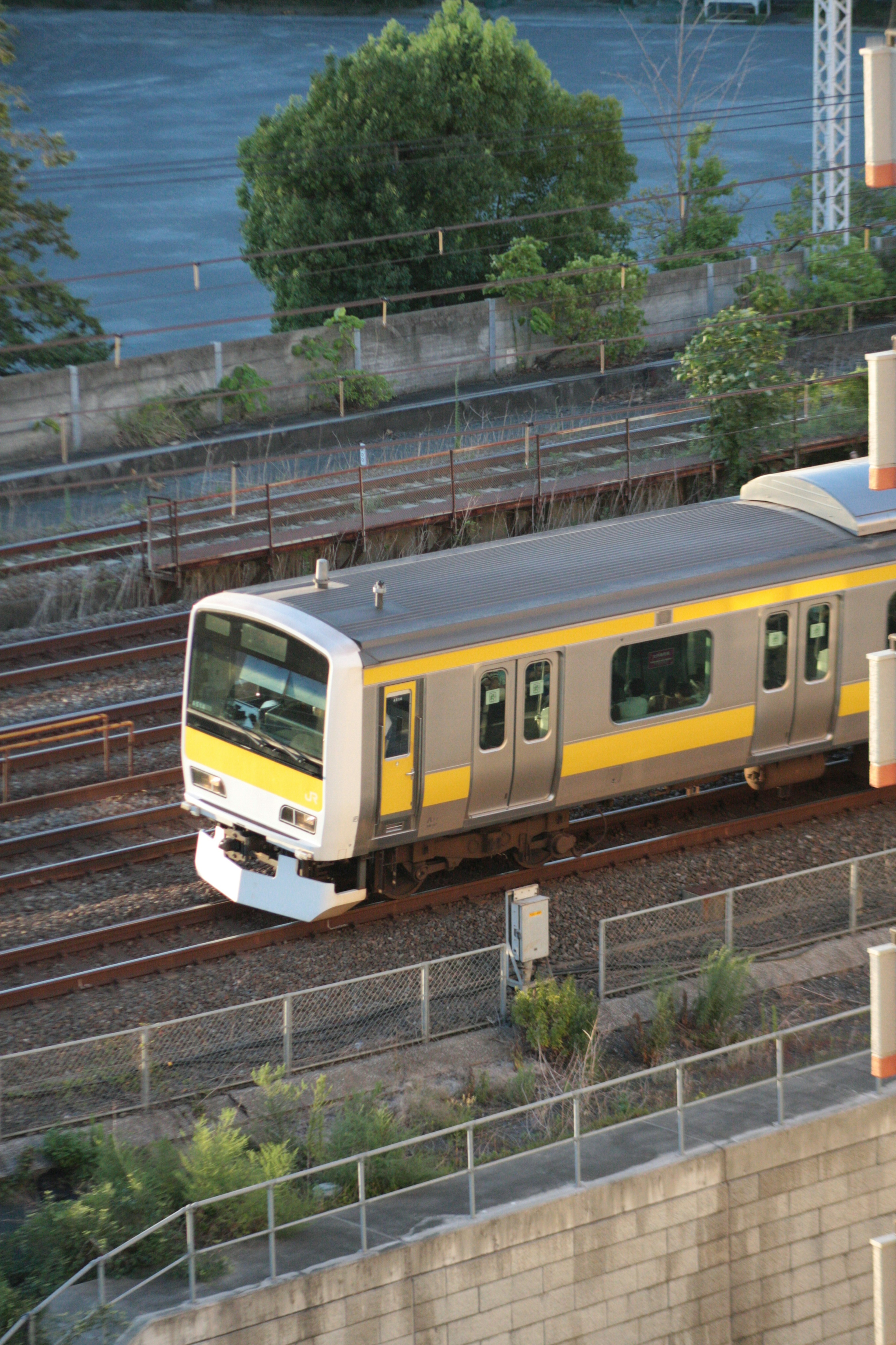 黄色と銀色の電車が線路を走行している風景