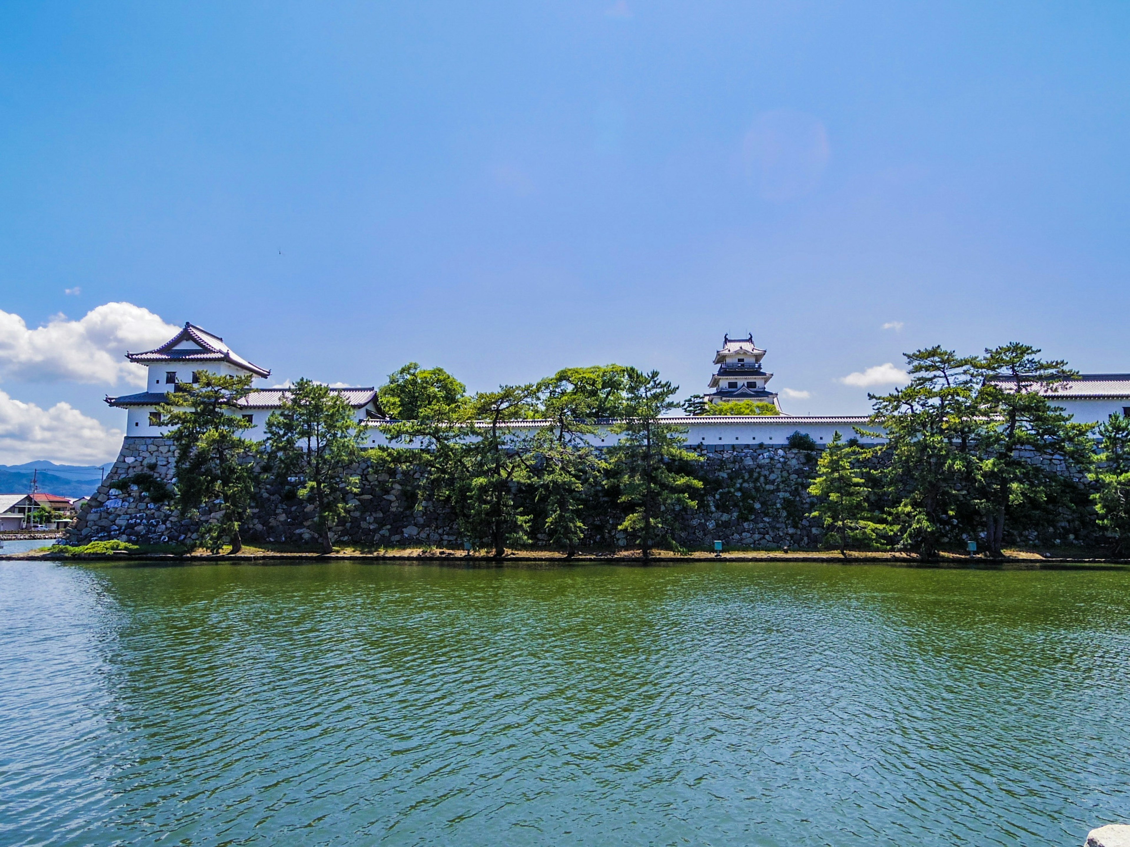 Castle exterior with a serene water view under a clear blue sky