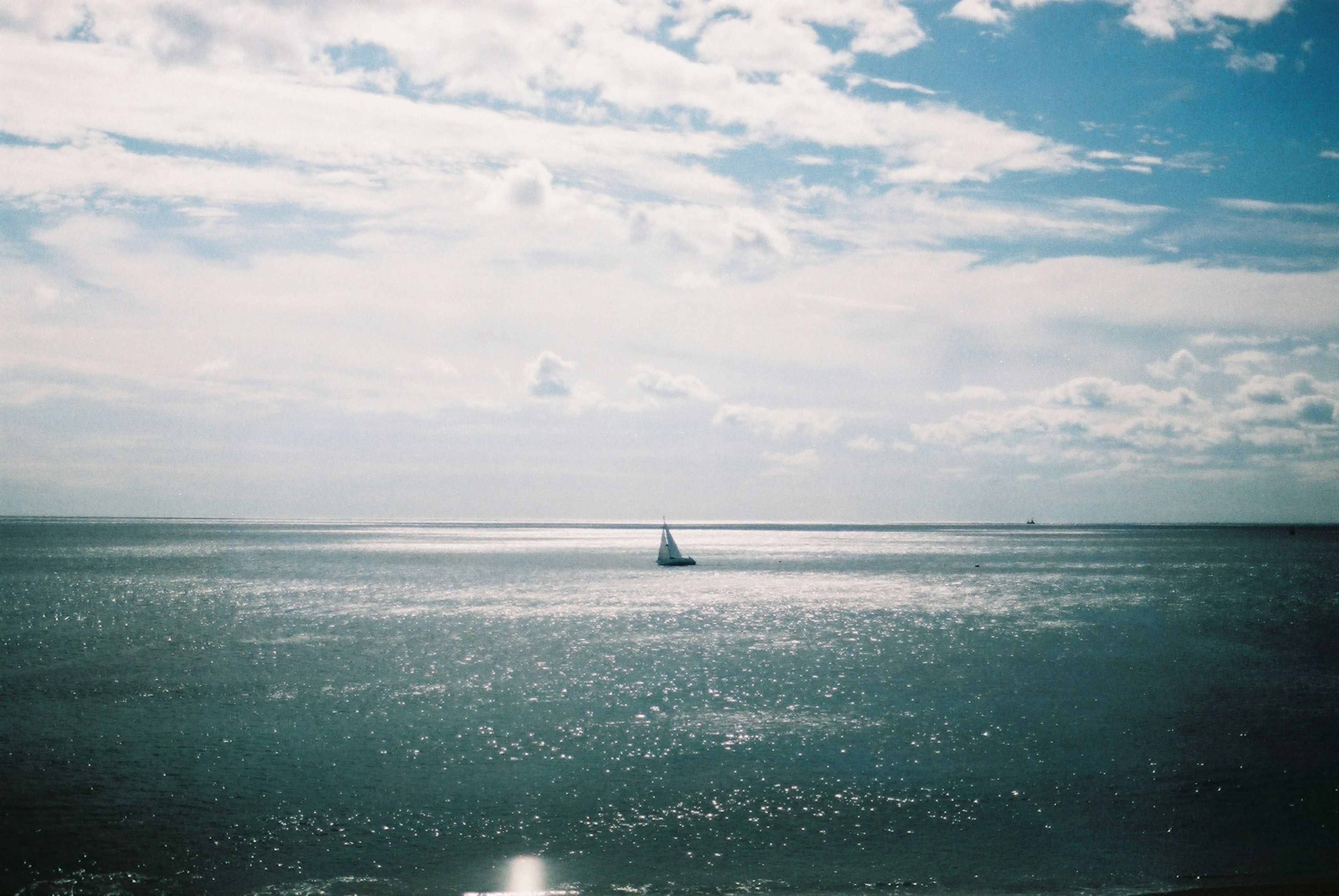 海の真ん中に浮かぶ小さな帆船と青い空