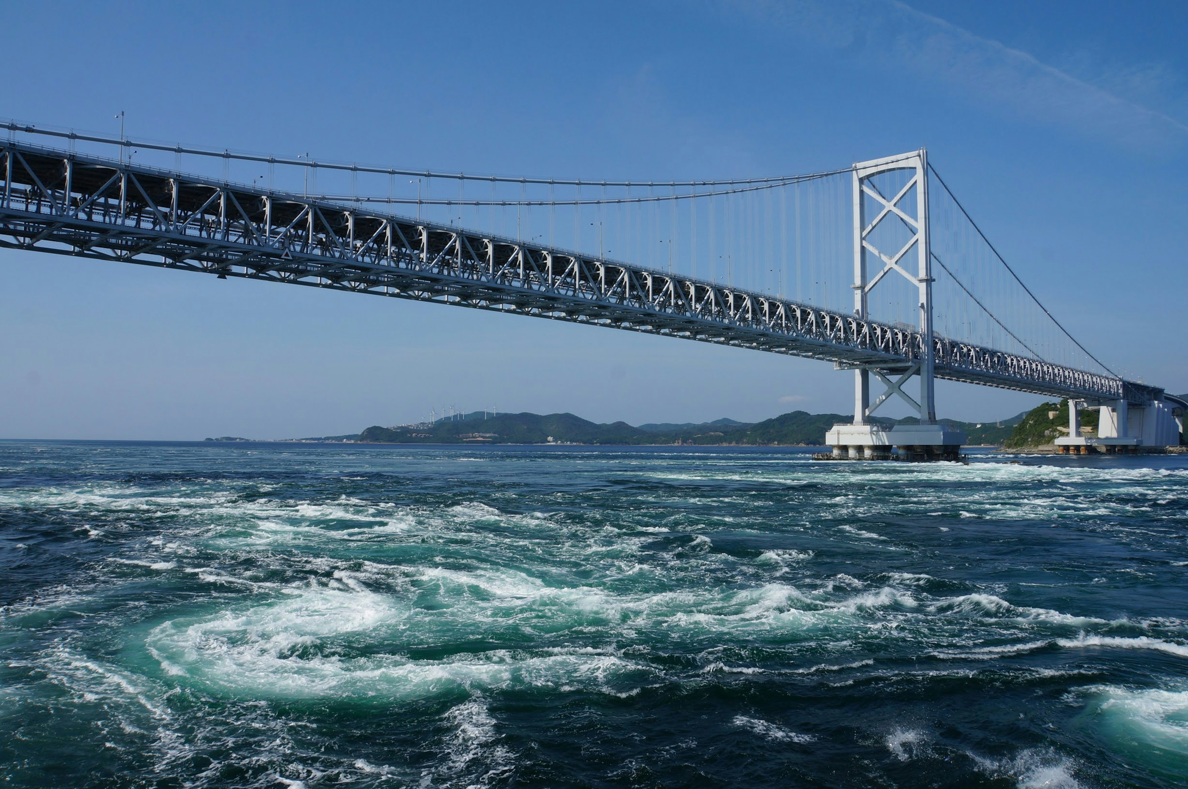 The Akashi Kaikyō Bridge spans over the sea with visible tidal swirls