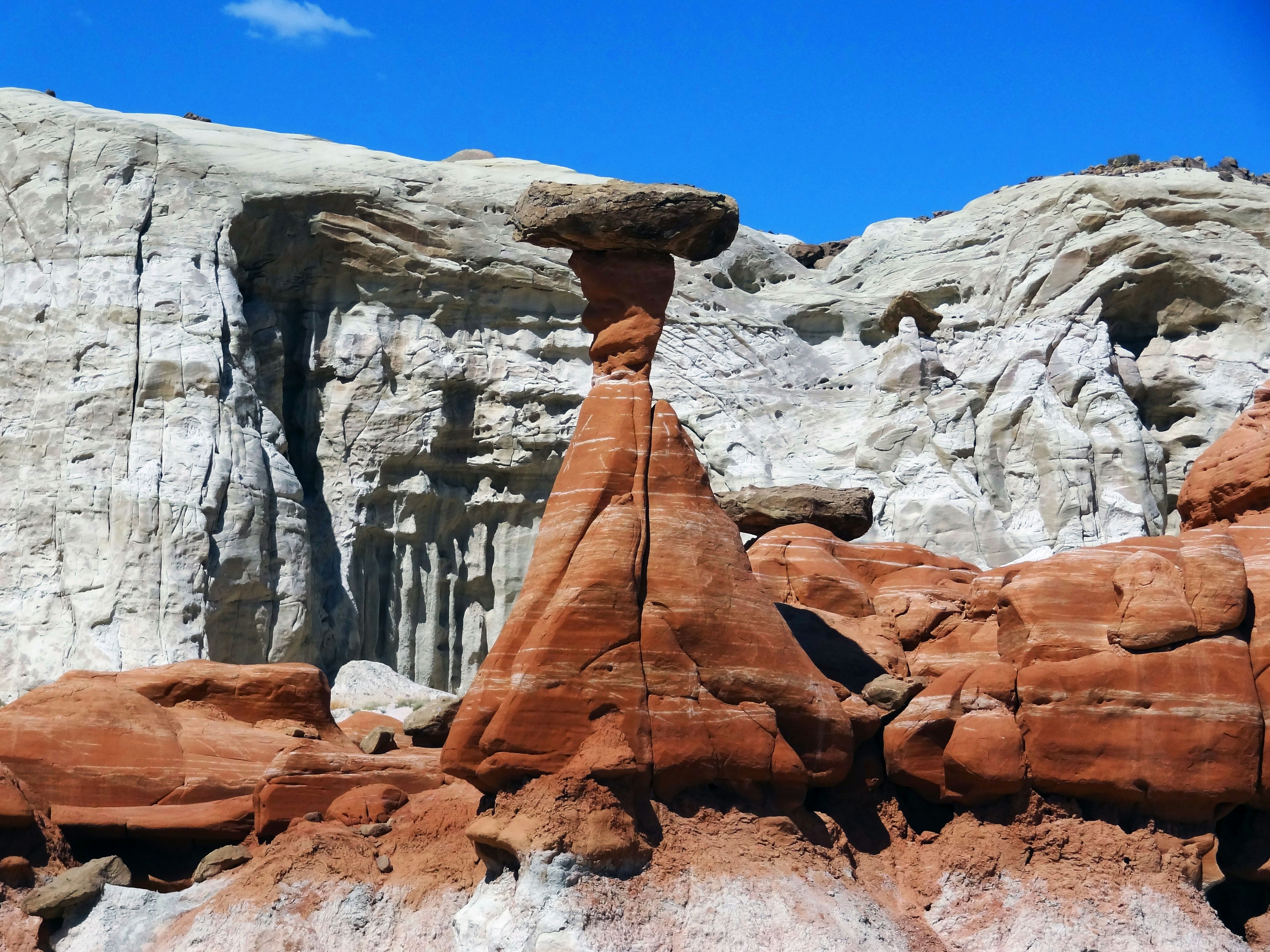 Unique rock formation with a red base and white cliffs in the background