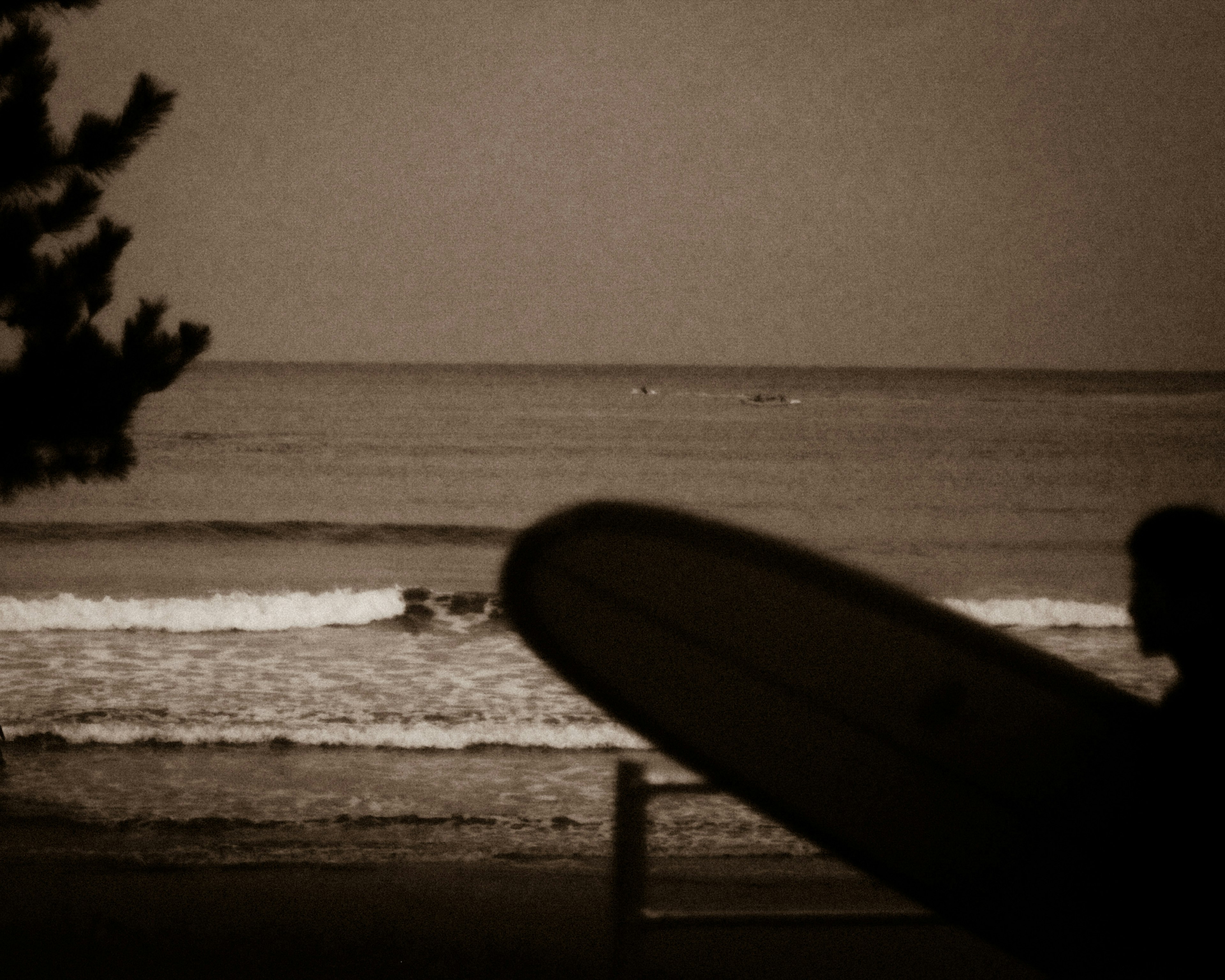 Silhouette of a person holding a surfboard against the ocean background