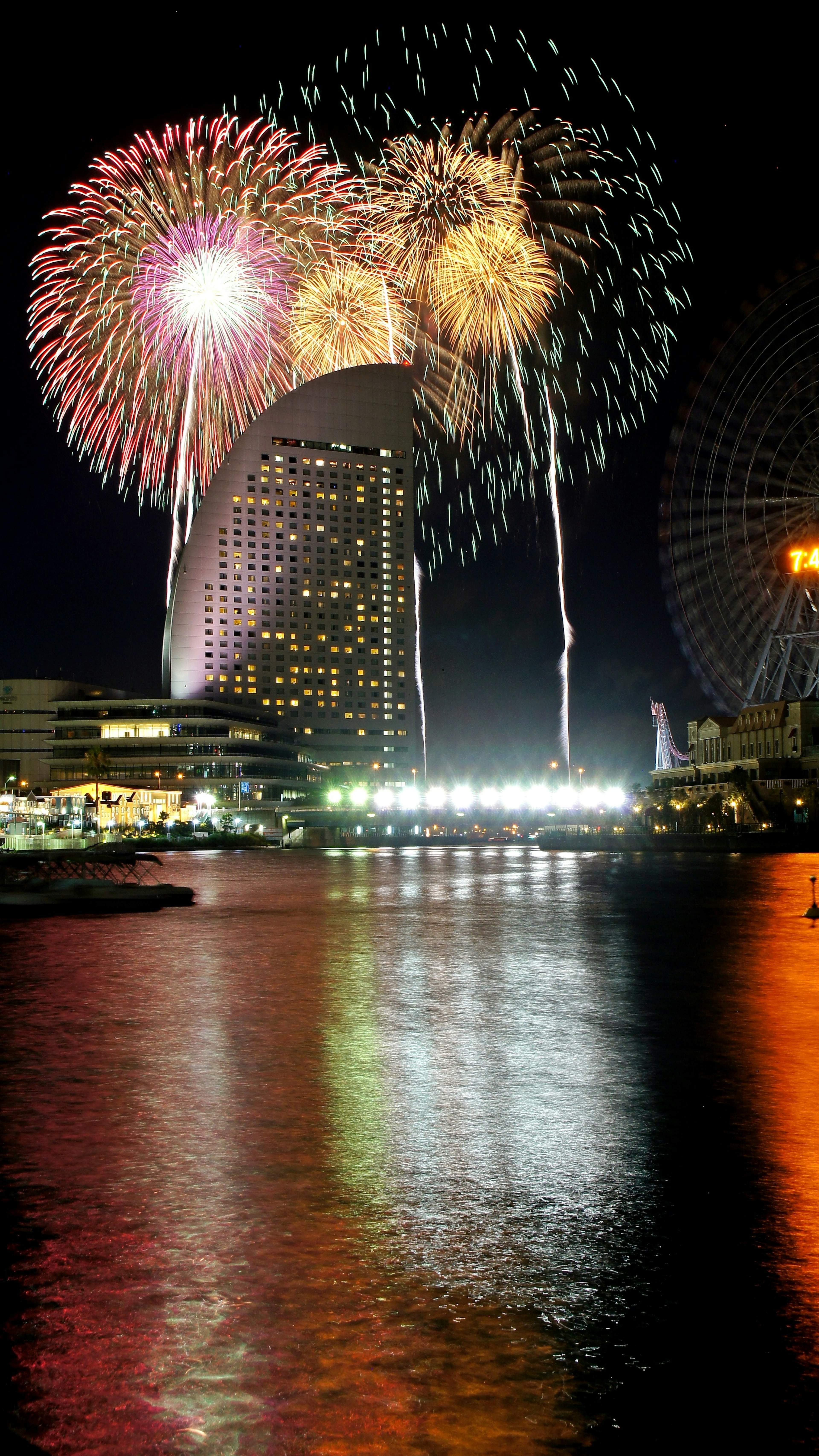 Spettacolo di fuochi d'artificio colorati su un fiume di notte con riflessi