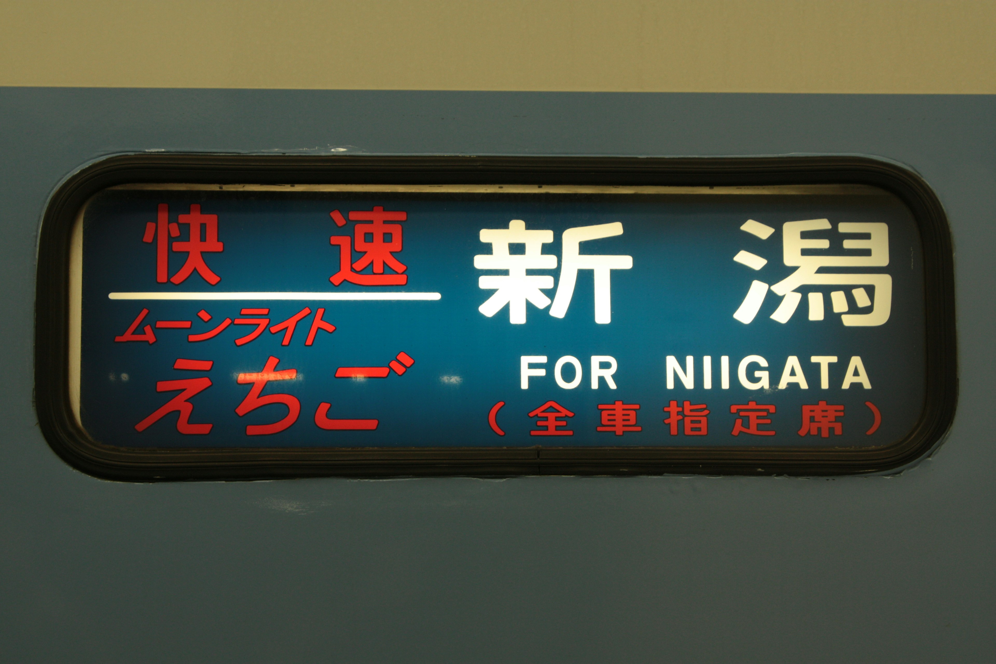 Train display board for Niigata with blue background and red white text