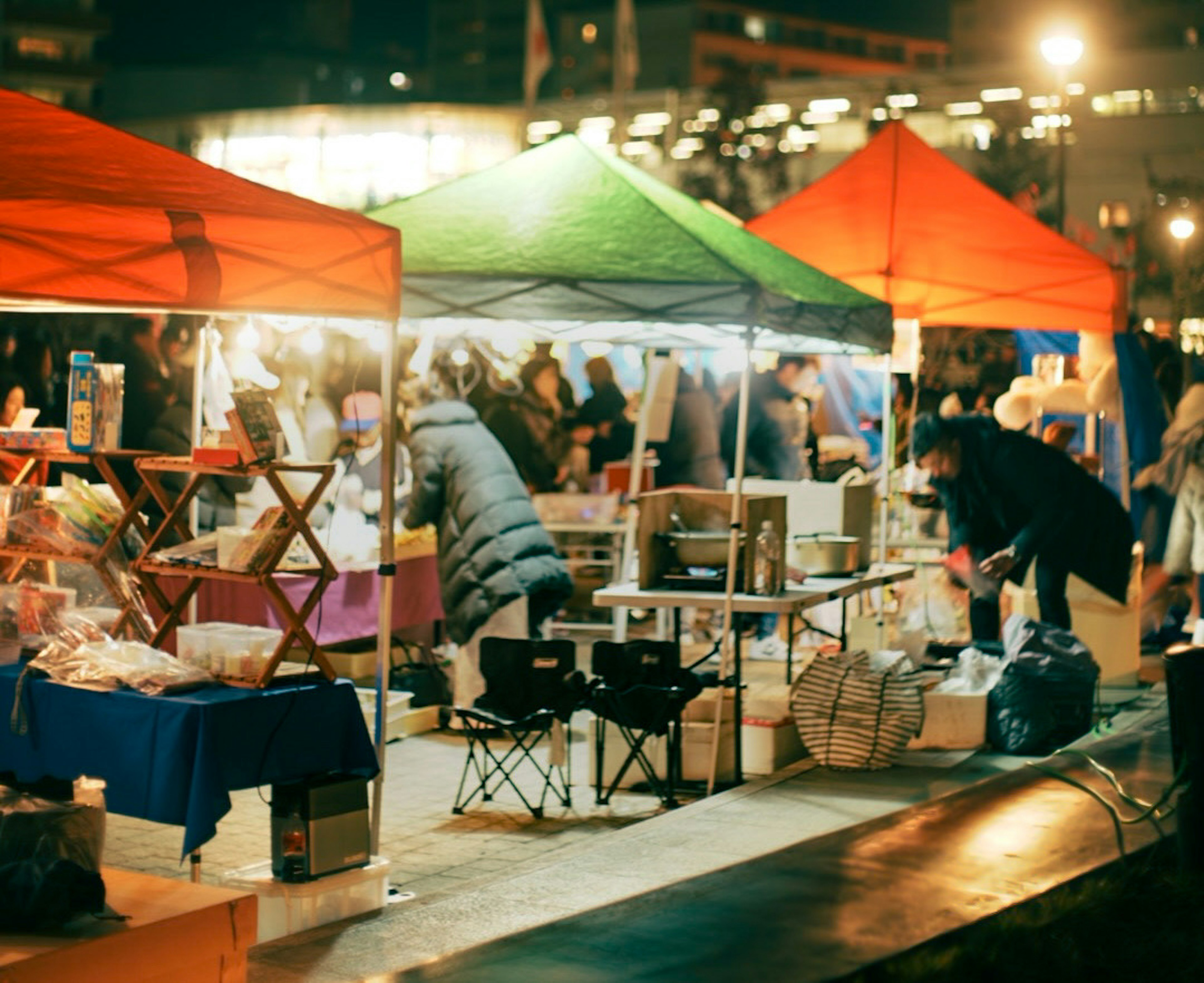 Scène de marché nocturne avec des tentes colorées et des vendeurs occupés