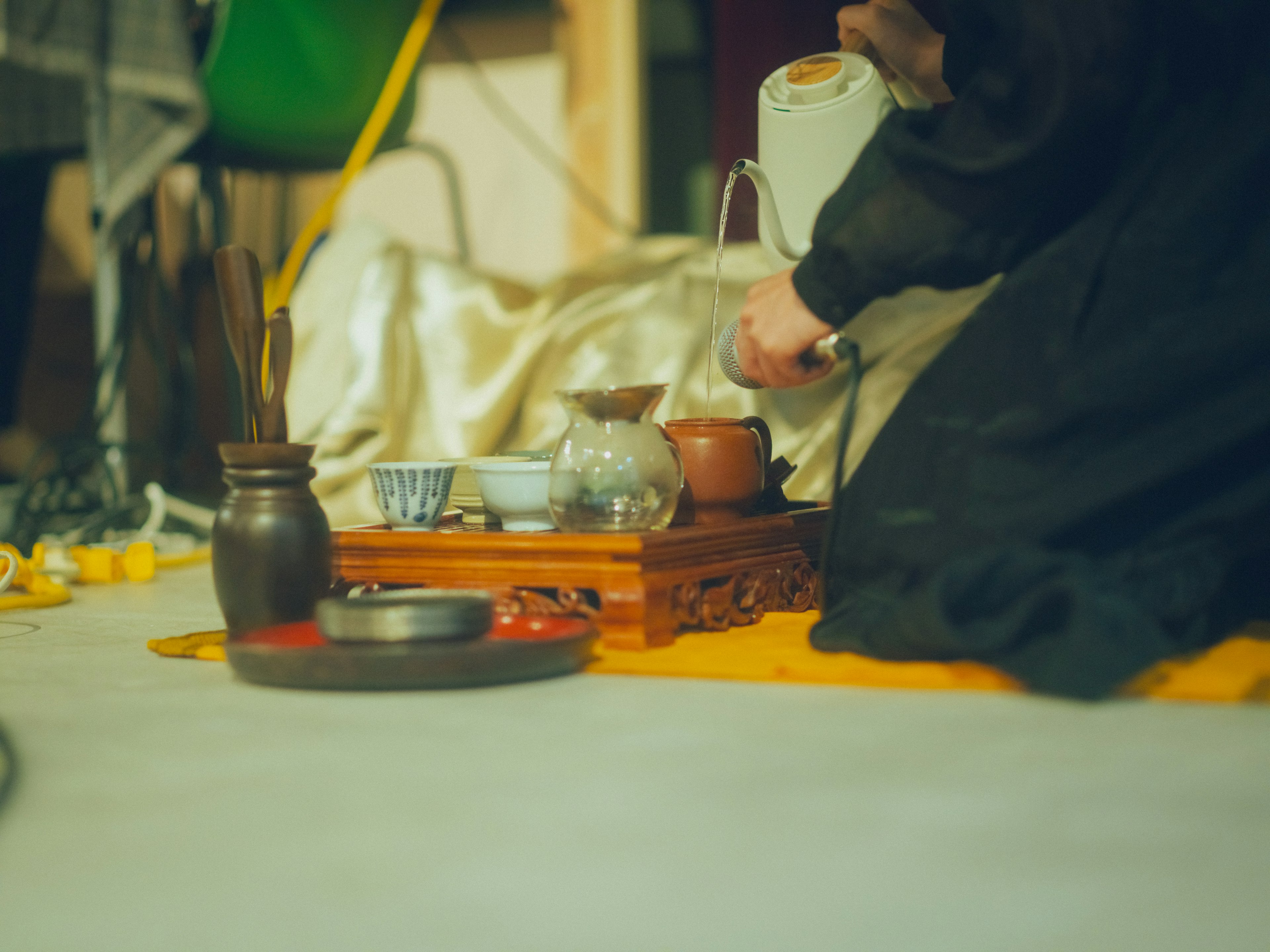 Manos preparando té con utensilios tradicionales sobre una estera