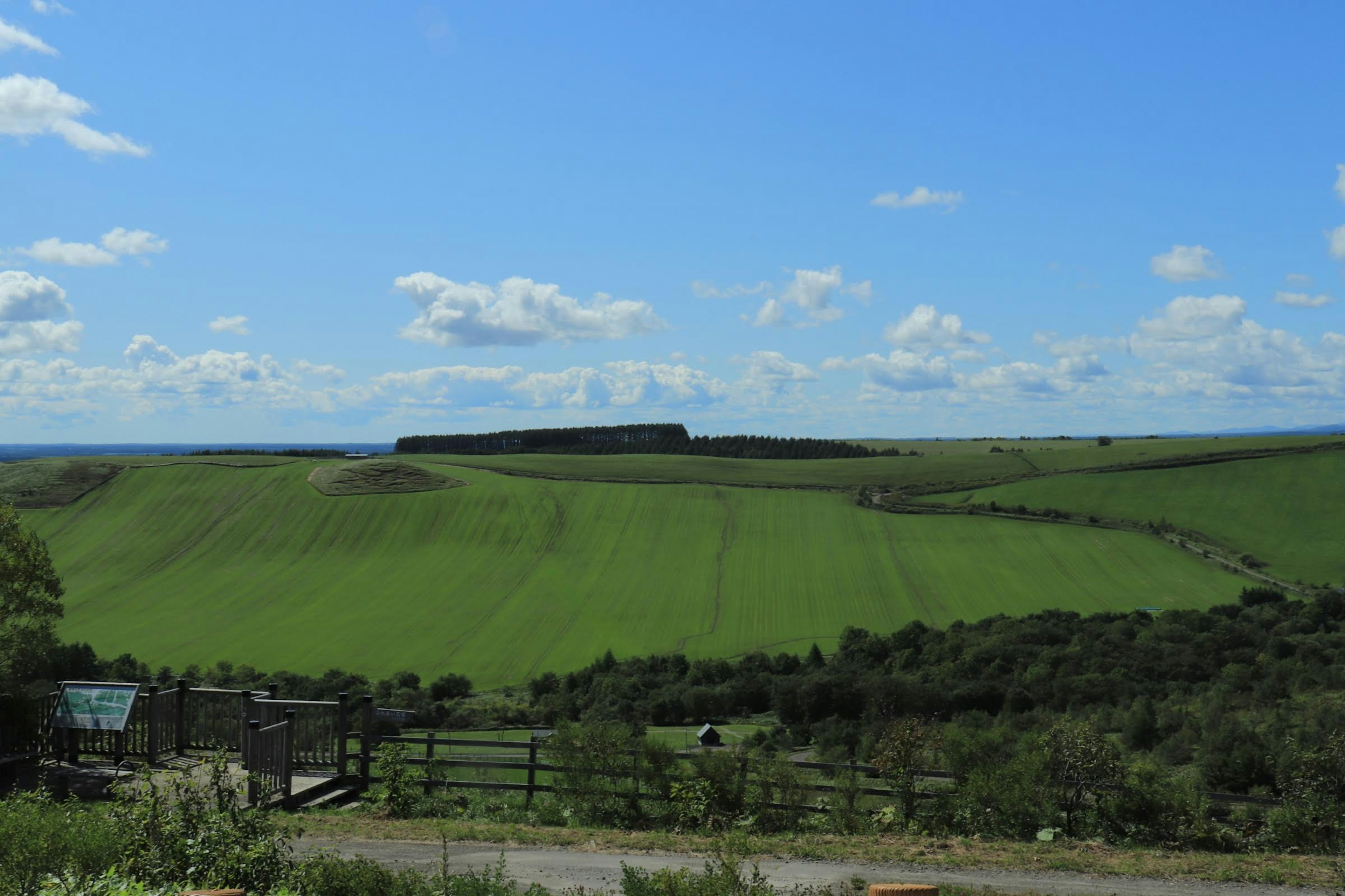 Vastes collines vertes sous un ciel bleu avec des nuages