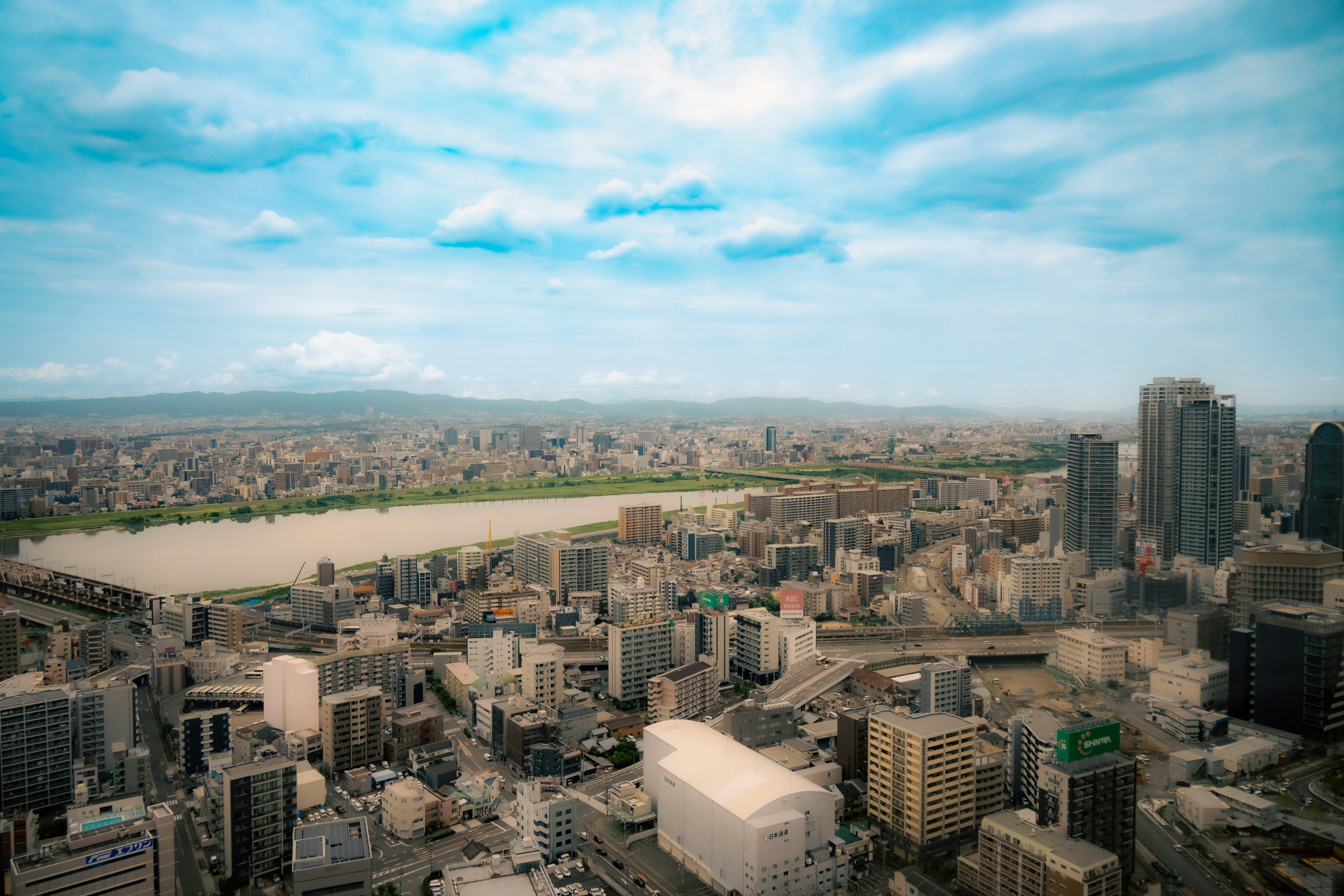 Aerial view of a city skyline with a river and mountains in the background