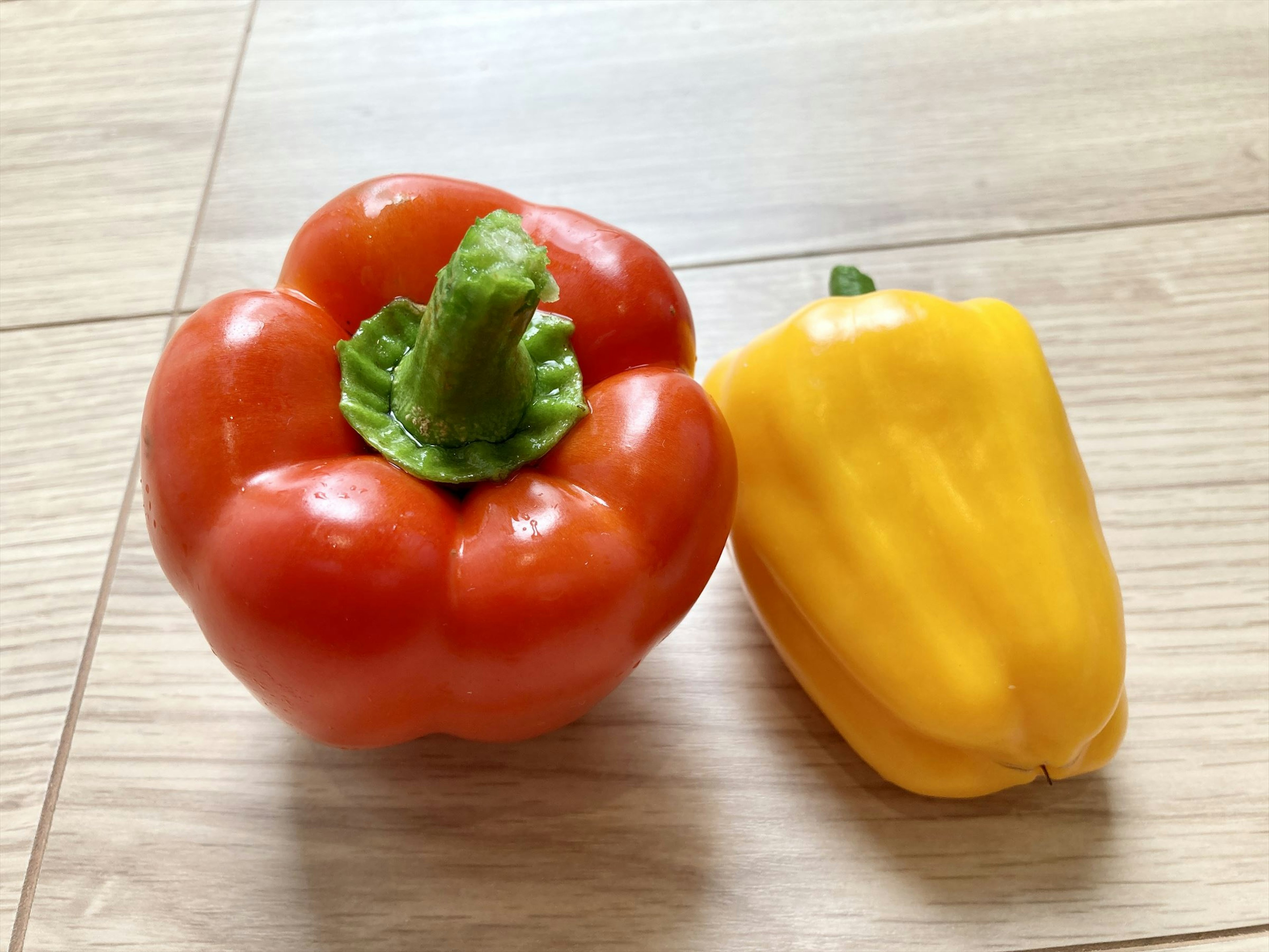 Red and yellow bell peppers placed on a wooden table