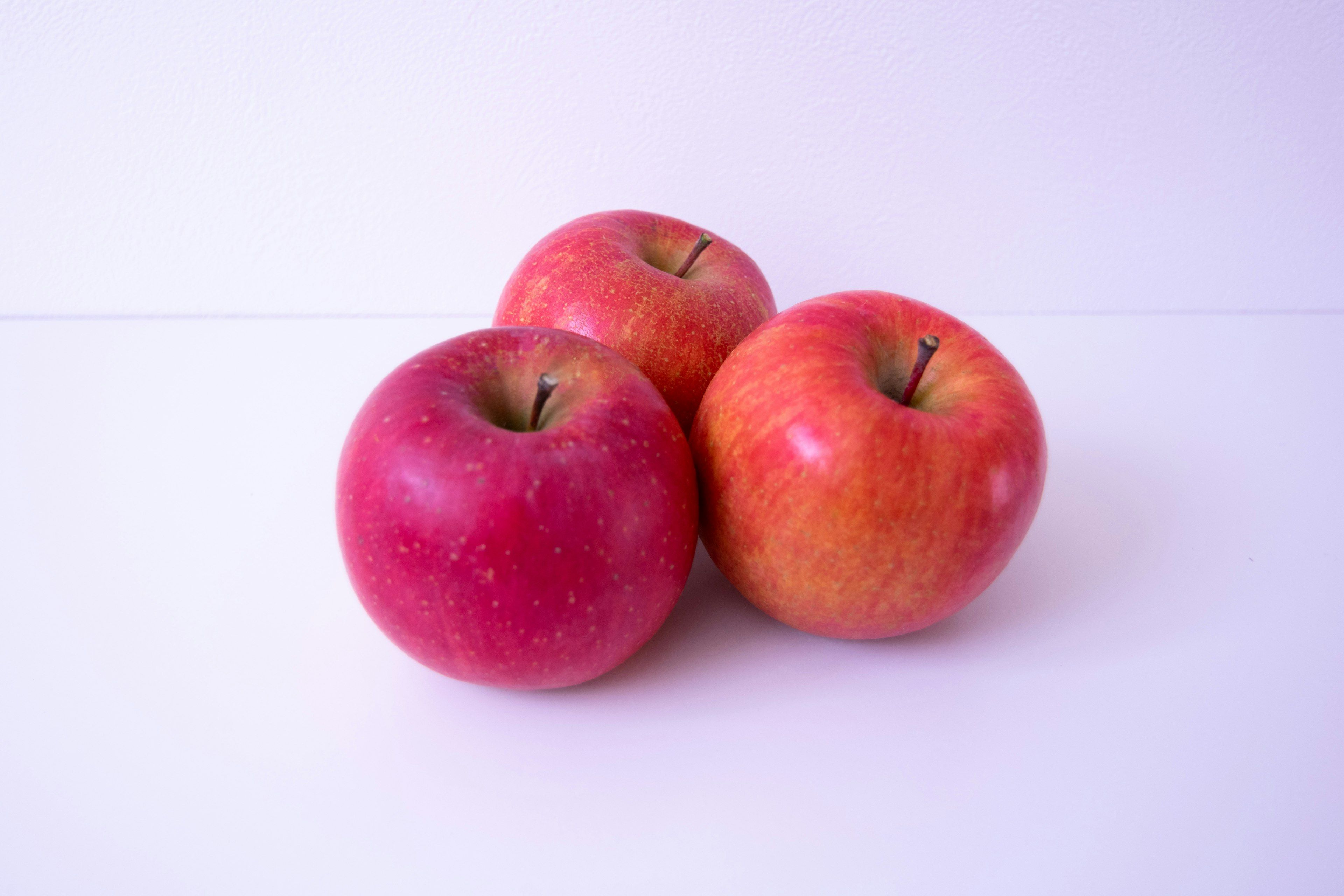 Tres manzanas rojas dispuestas juntas sobre un fondo blanco