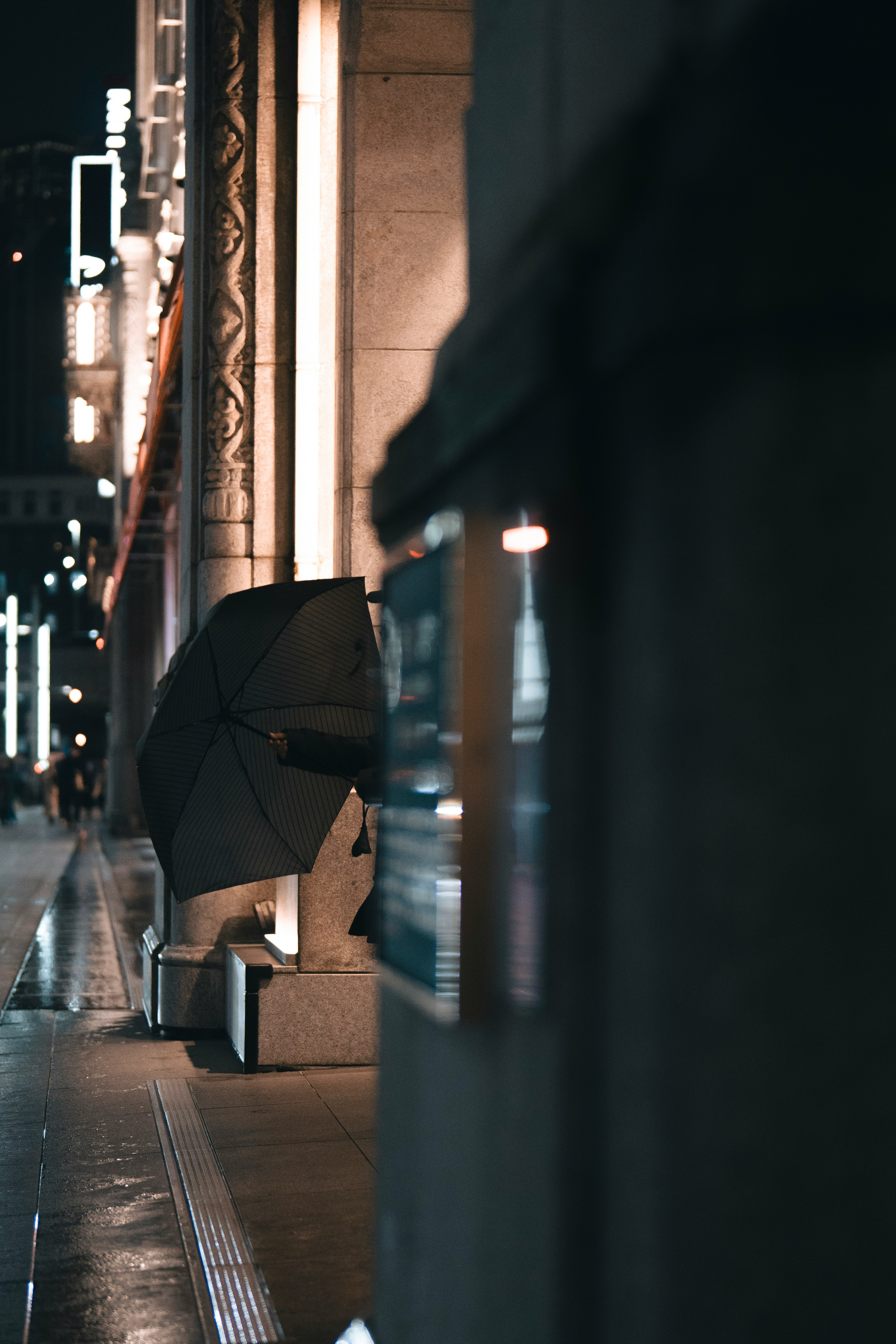 A black umbrella is placed on a street corner at night