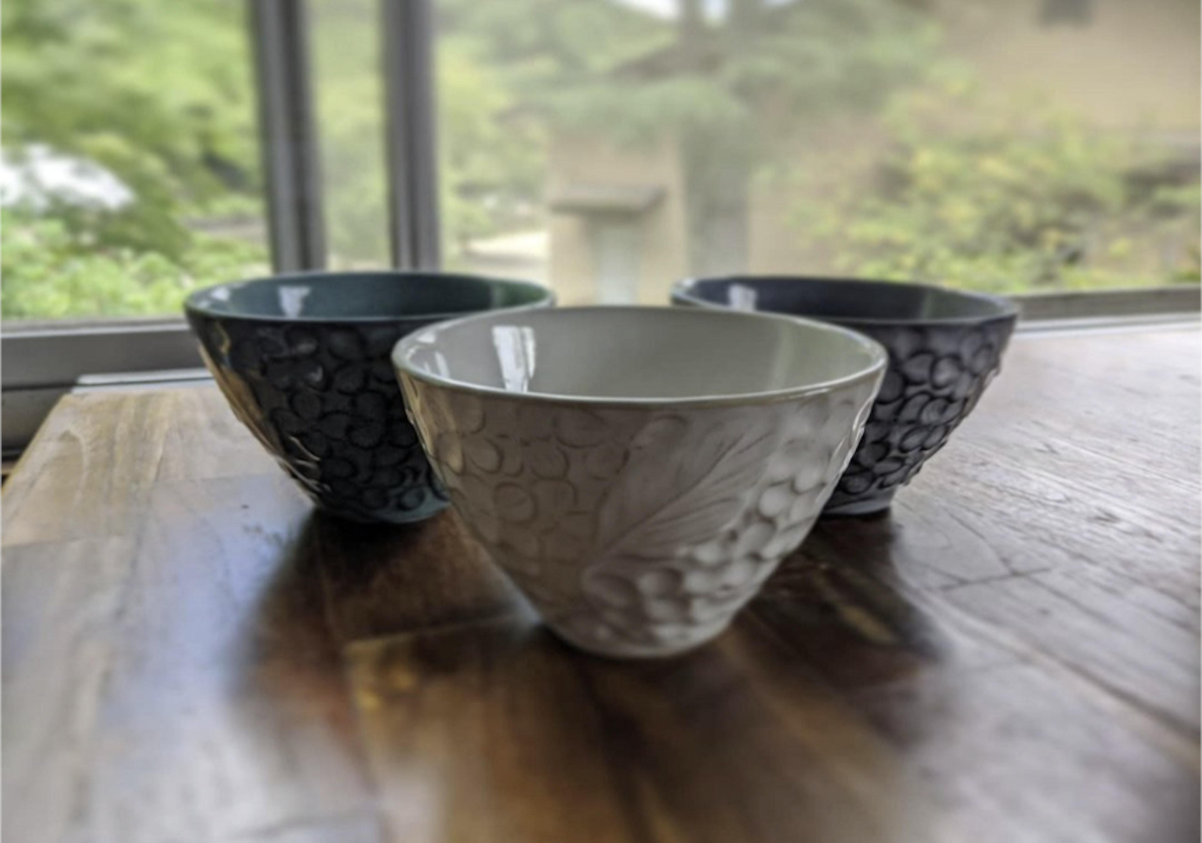 Three different colored and designed bowls on a wooden table