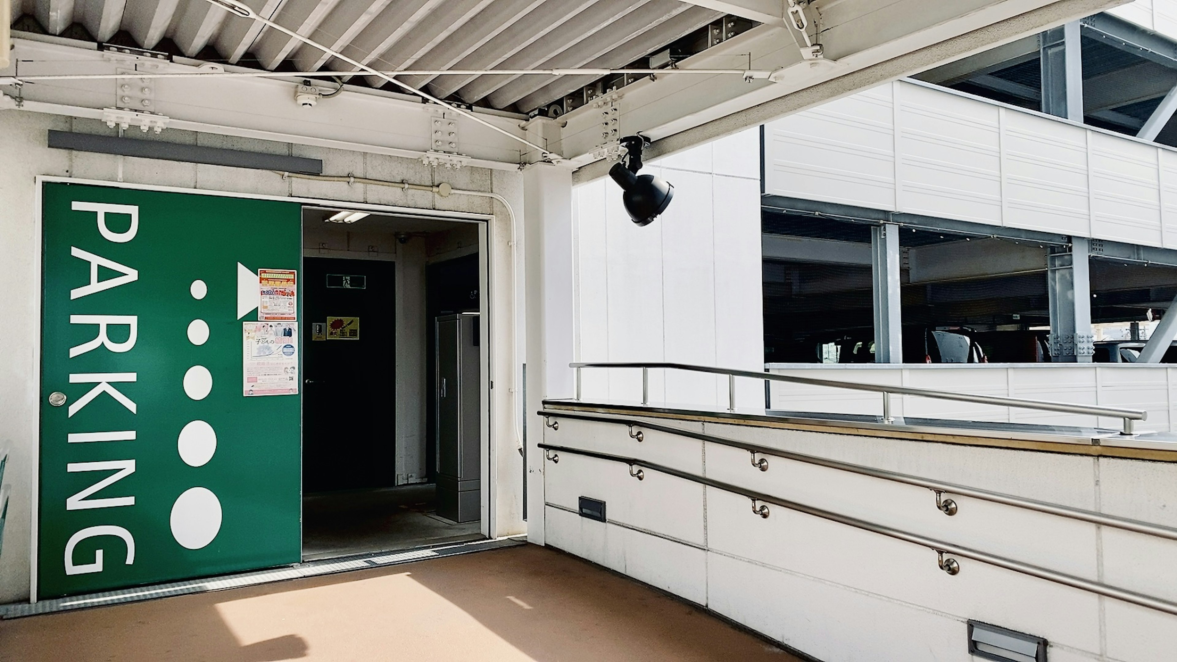 Entrée d'un parking avec un panneau vert et des murs blancs