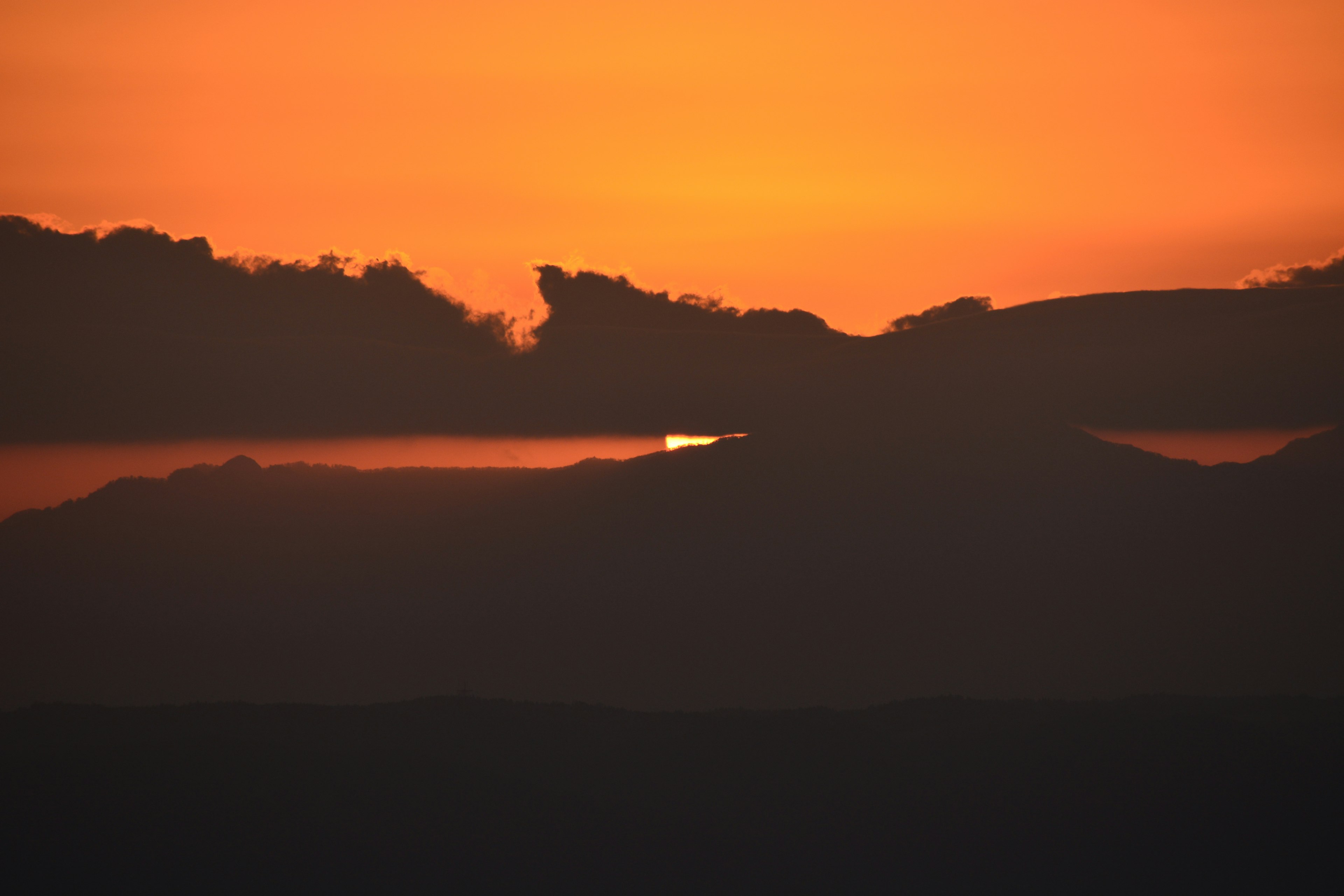 夕焼けのオレンジ色の空とシルエットの山々