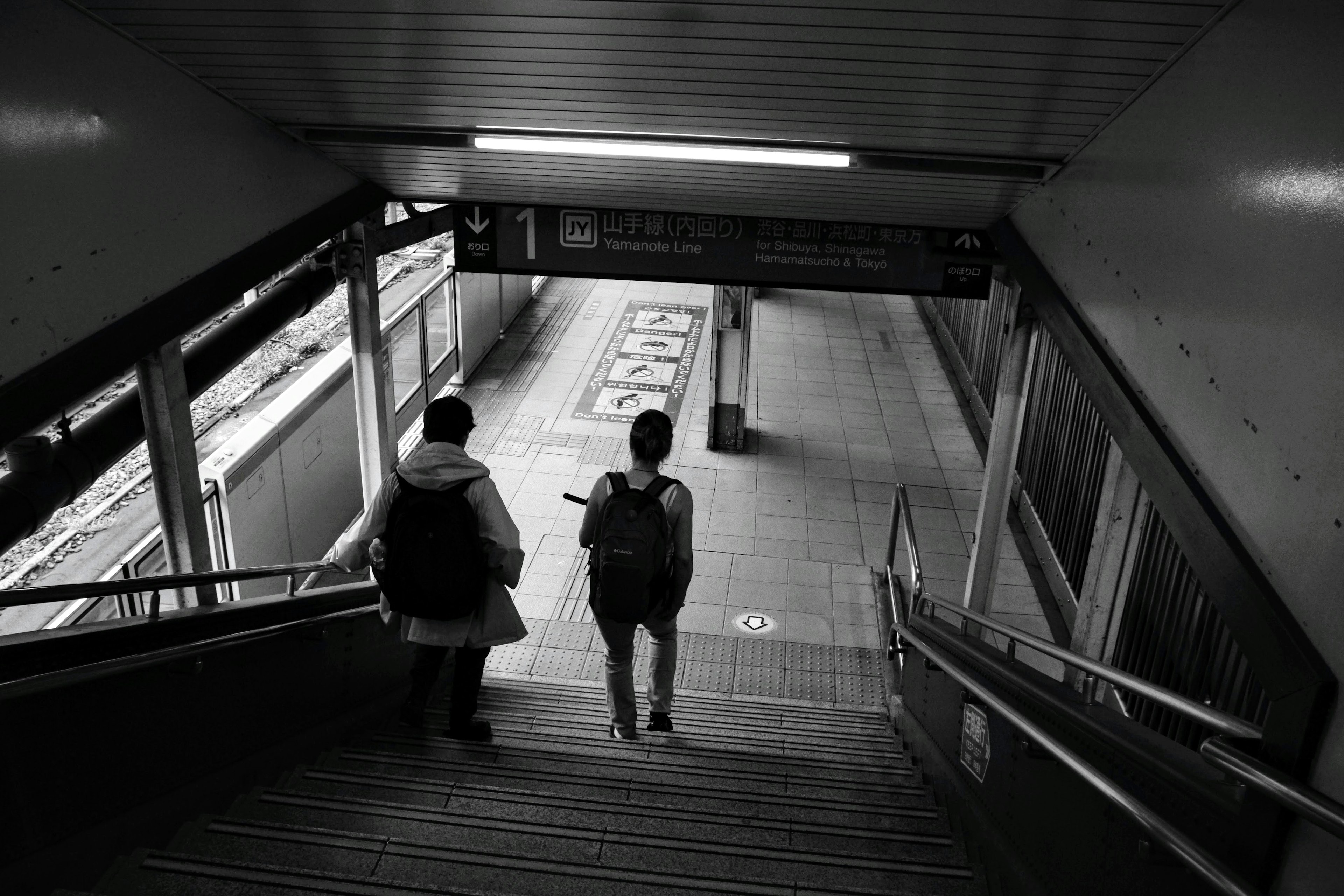 Zwei Personen, die Treppen in einem Bahnhof hinuntergehen