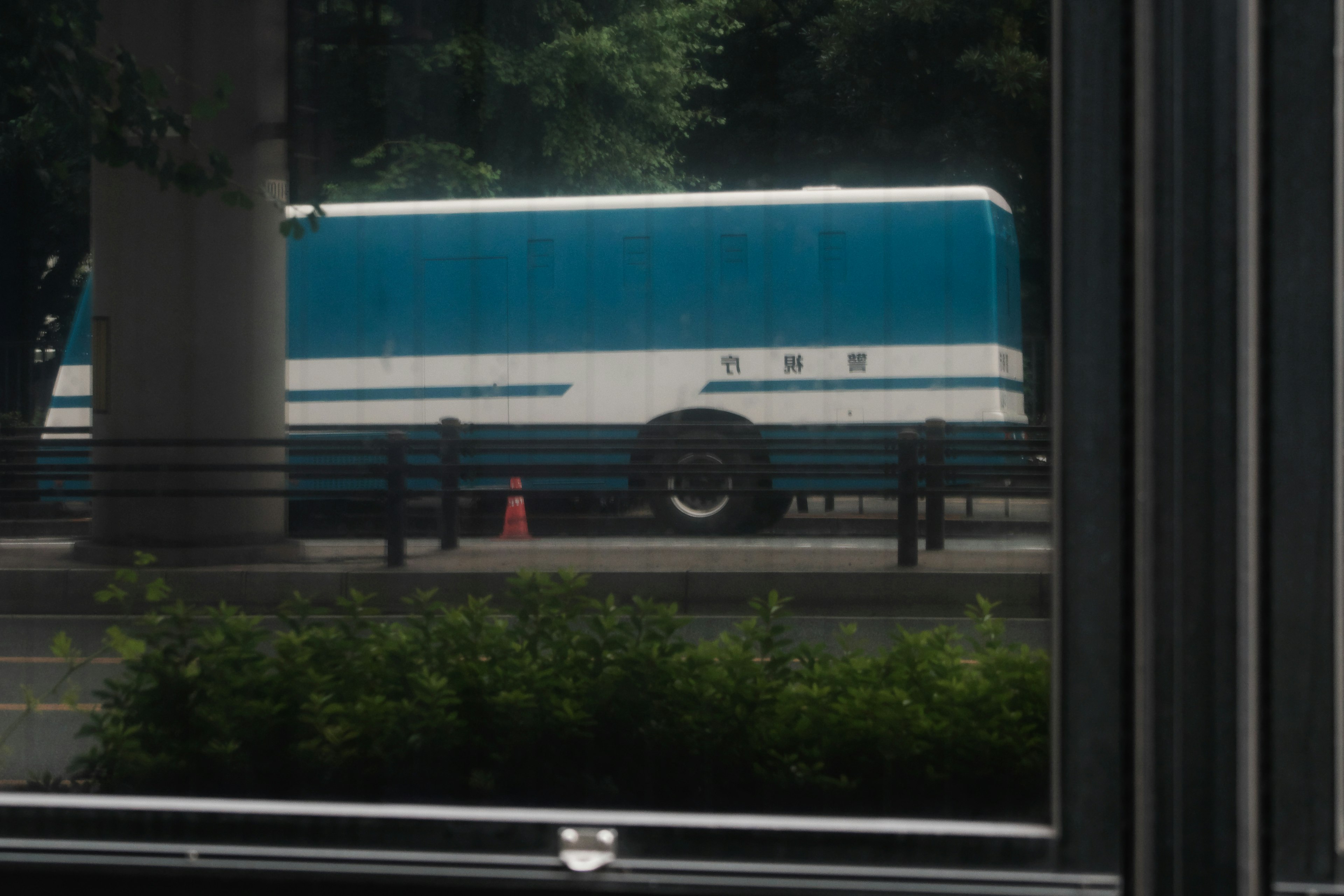 View of a blue and white bus seen through a window