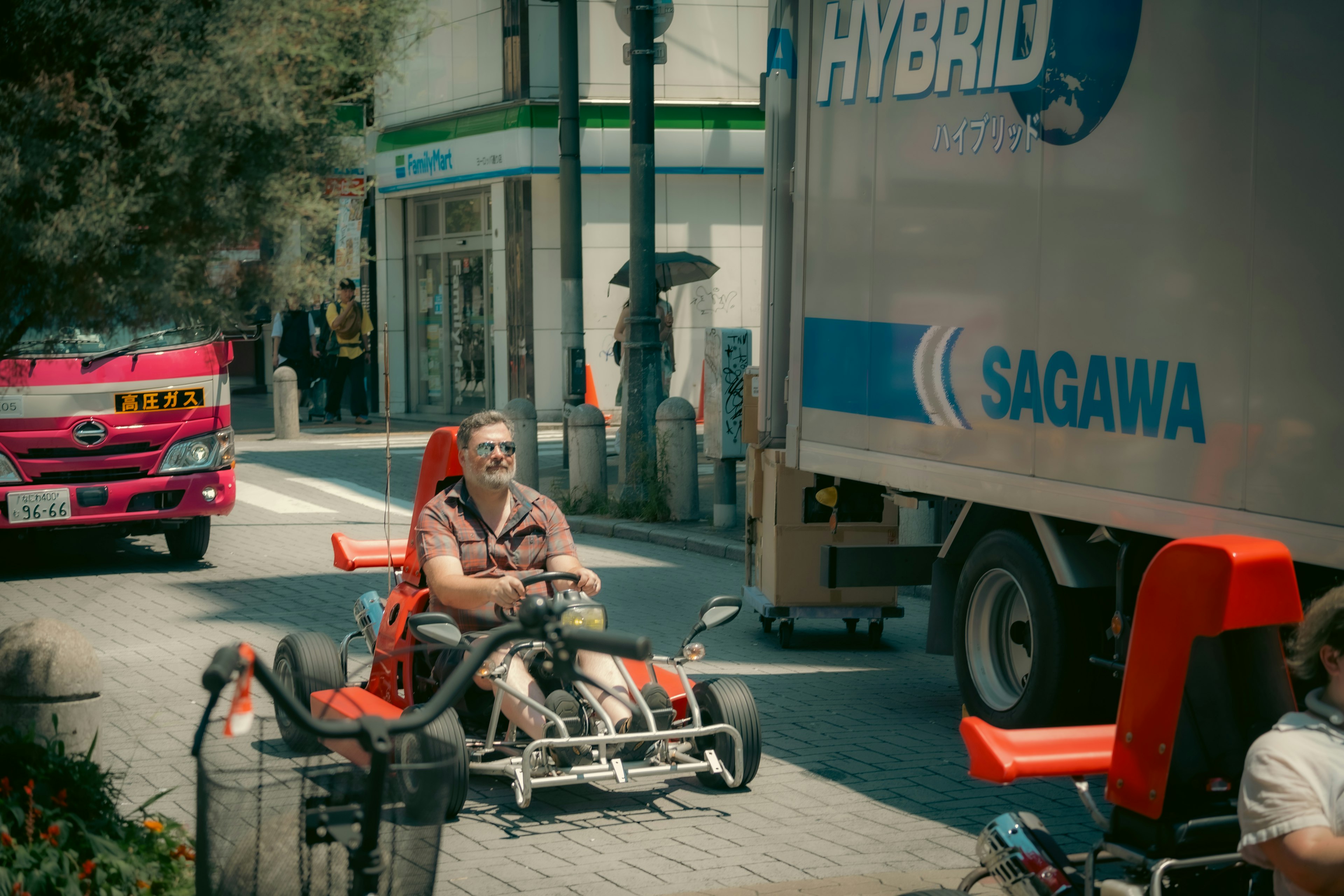 ゴーカートに乗る男性とトラックが通る街の風景