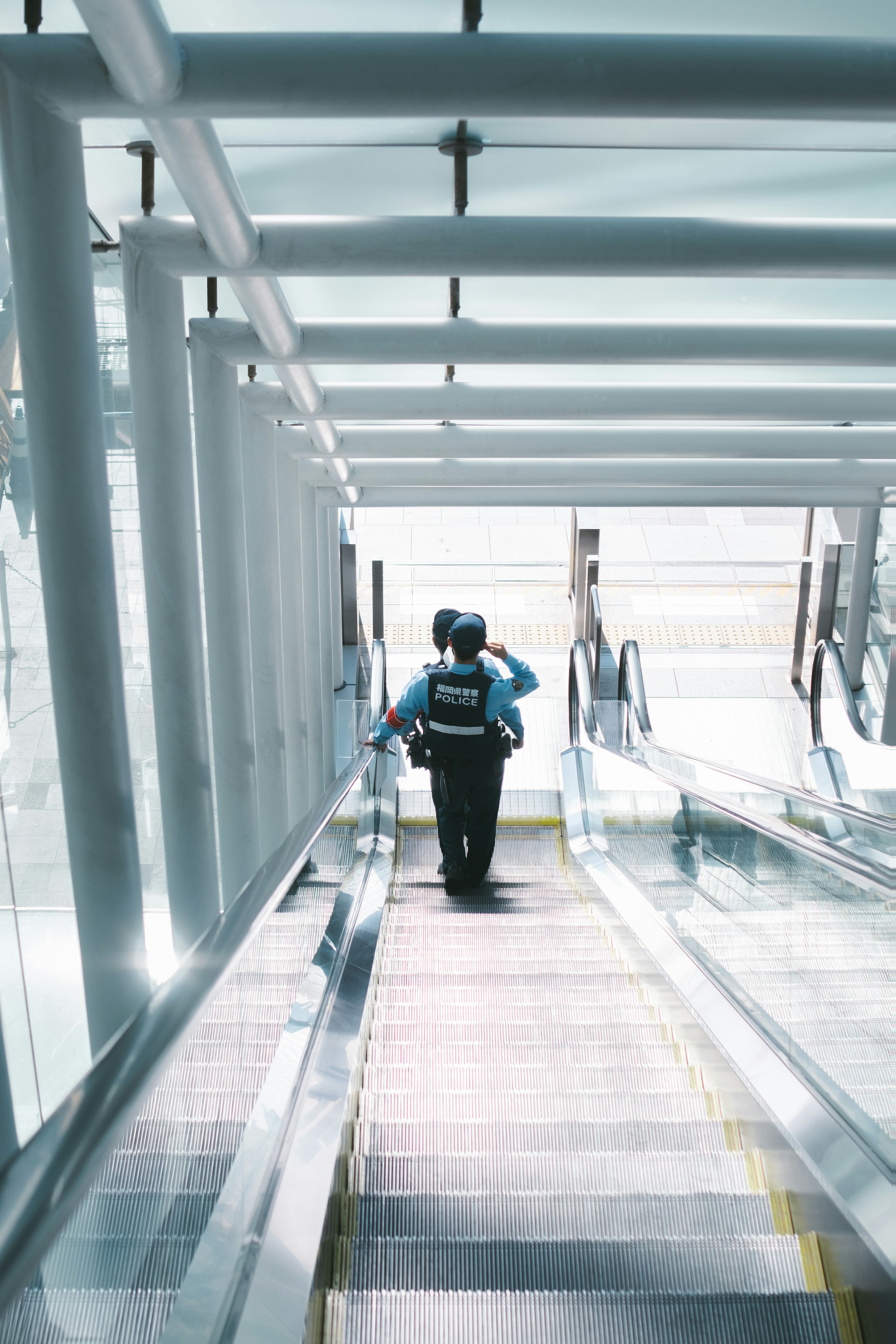 Person in blue shirt walking down escalator