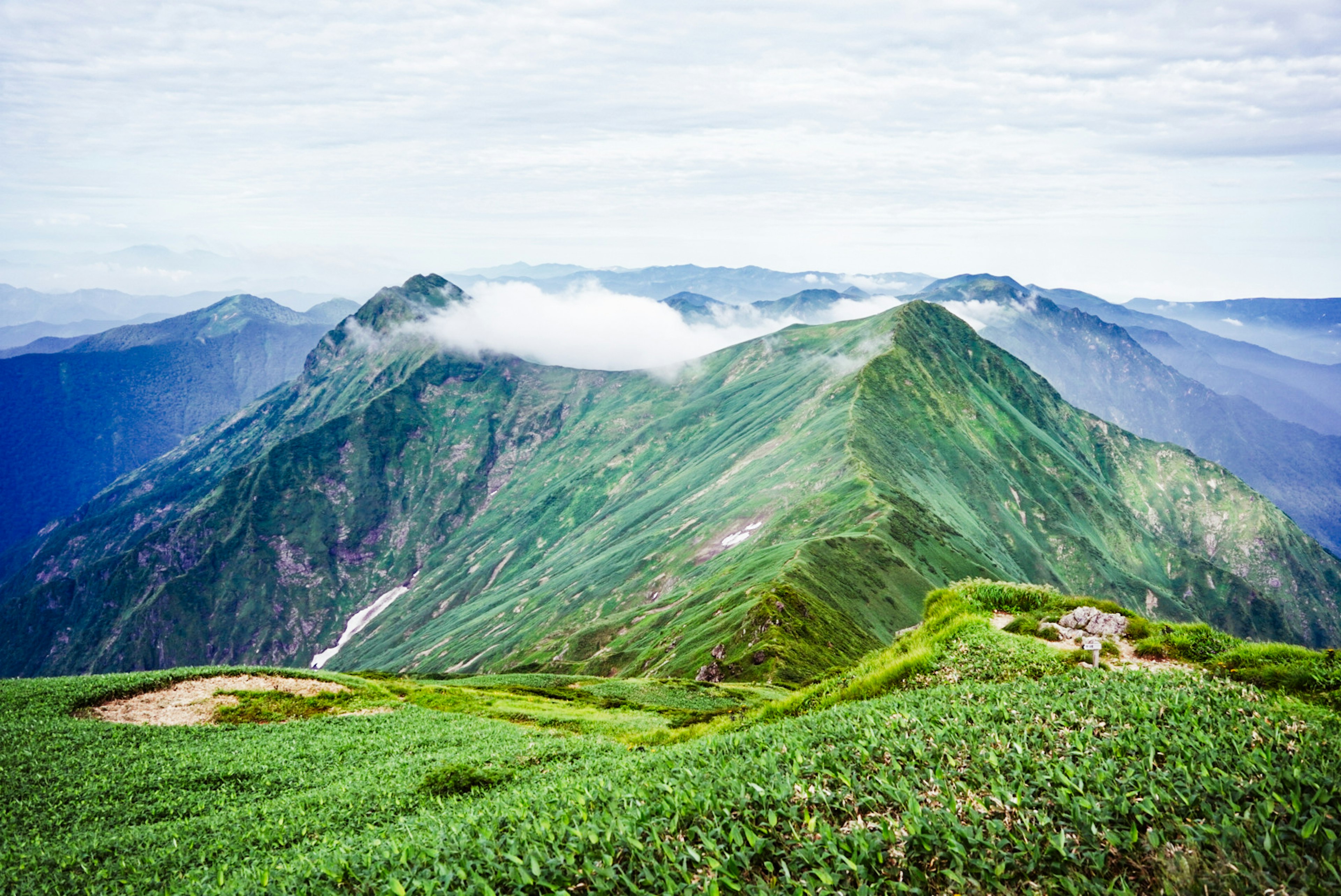 Paesaggio montano verdeggiante con cime coperte di nuvole