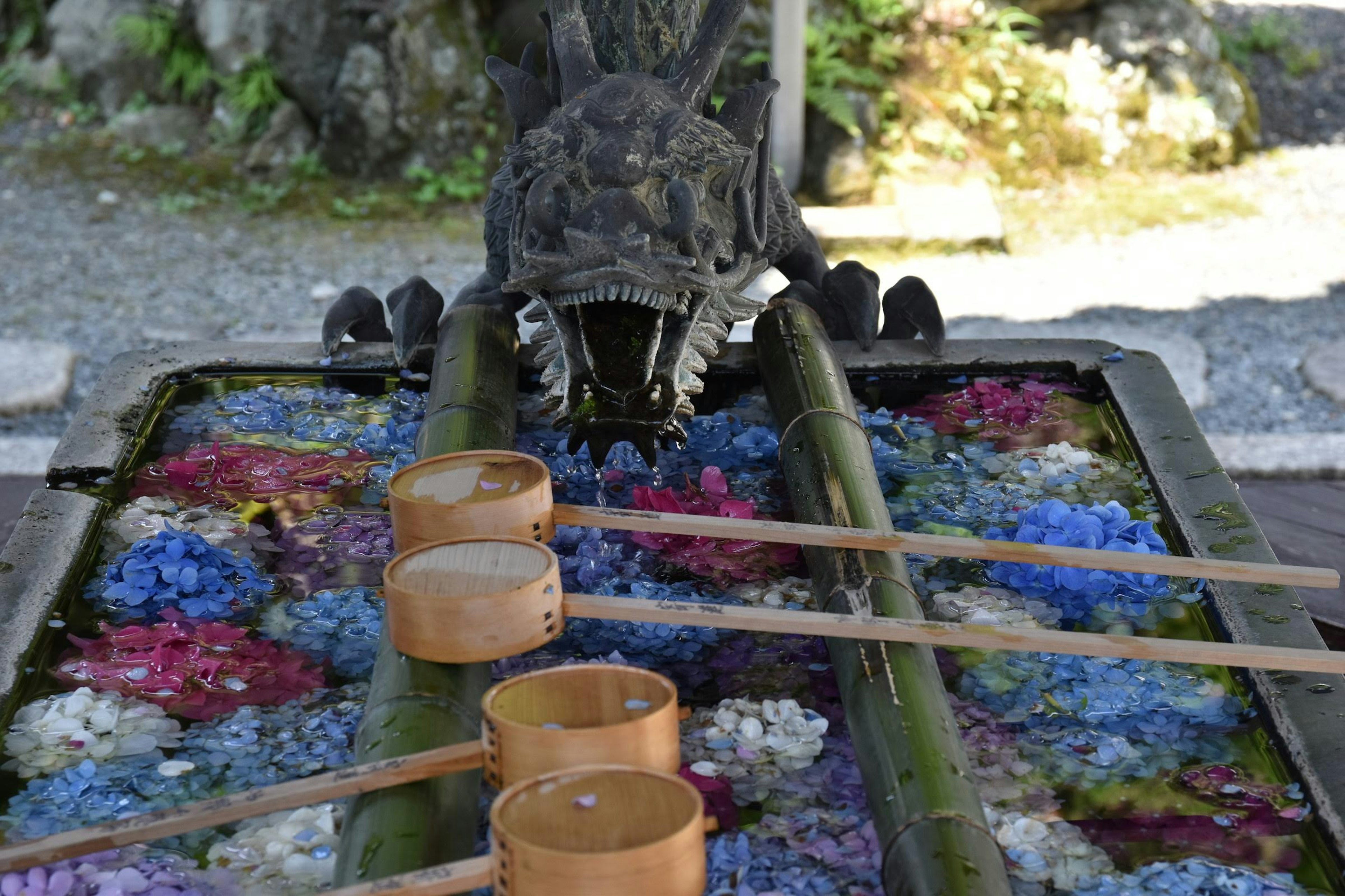 Bassin d'eau en bambou avec des fleurs colorées et une sculpture de dragon