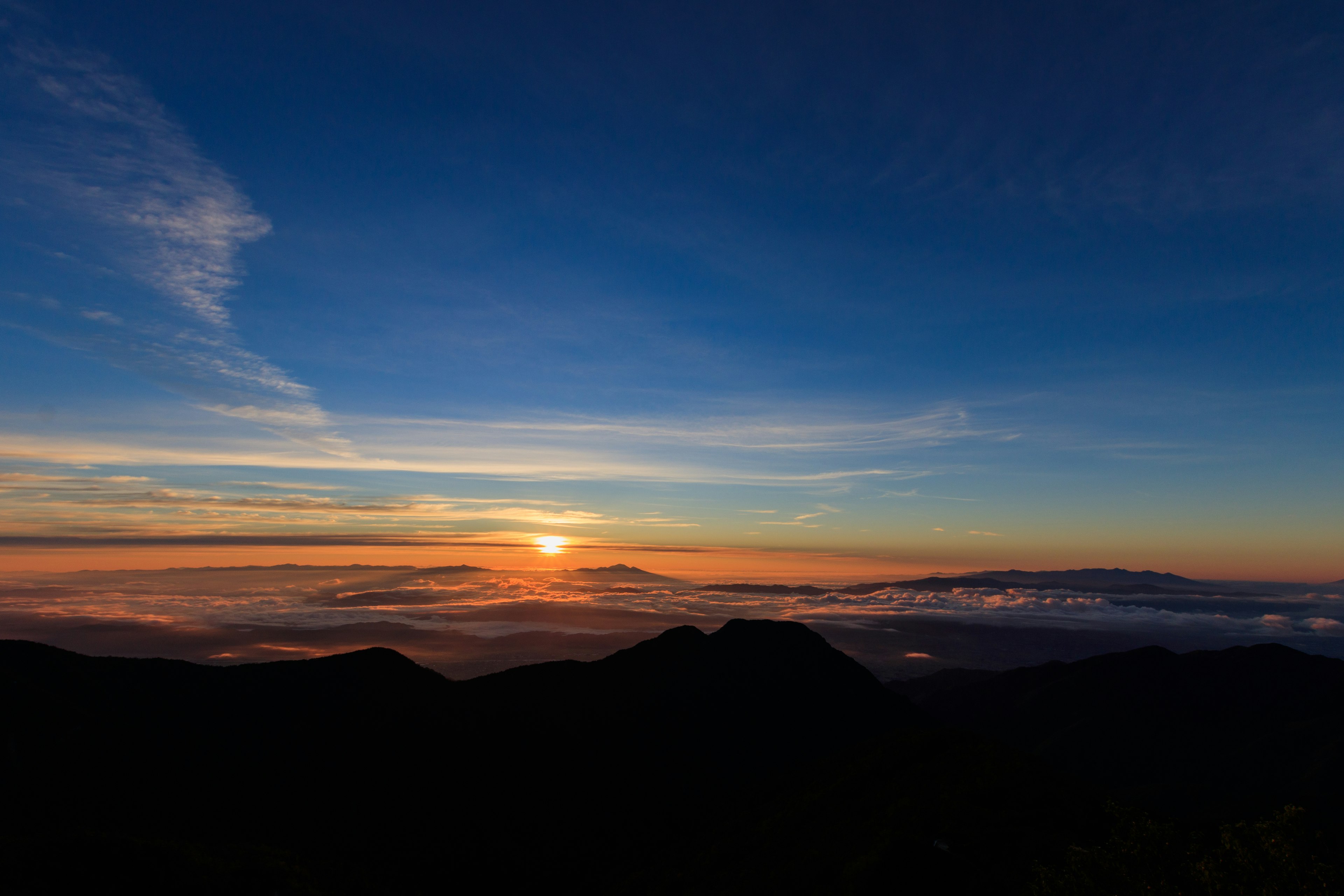 Pemandangan matahari terbit yang indah di atas lautan awan dengan siluet gunung