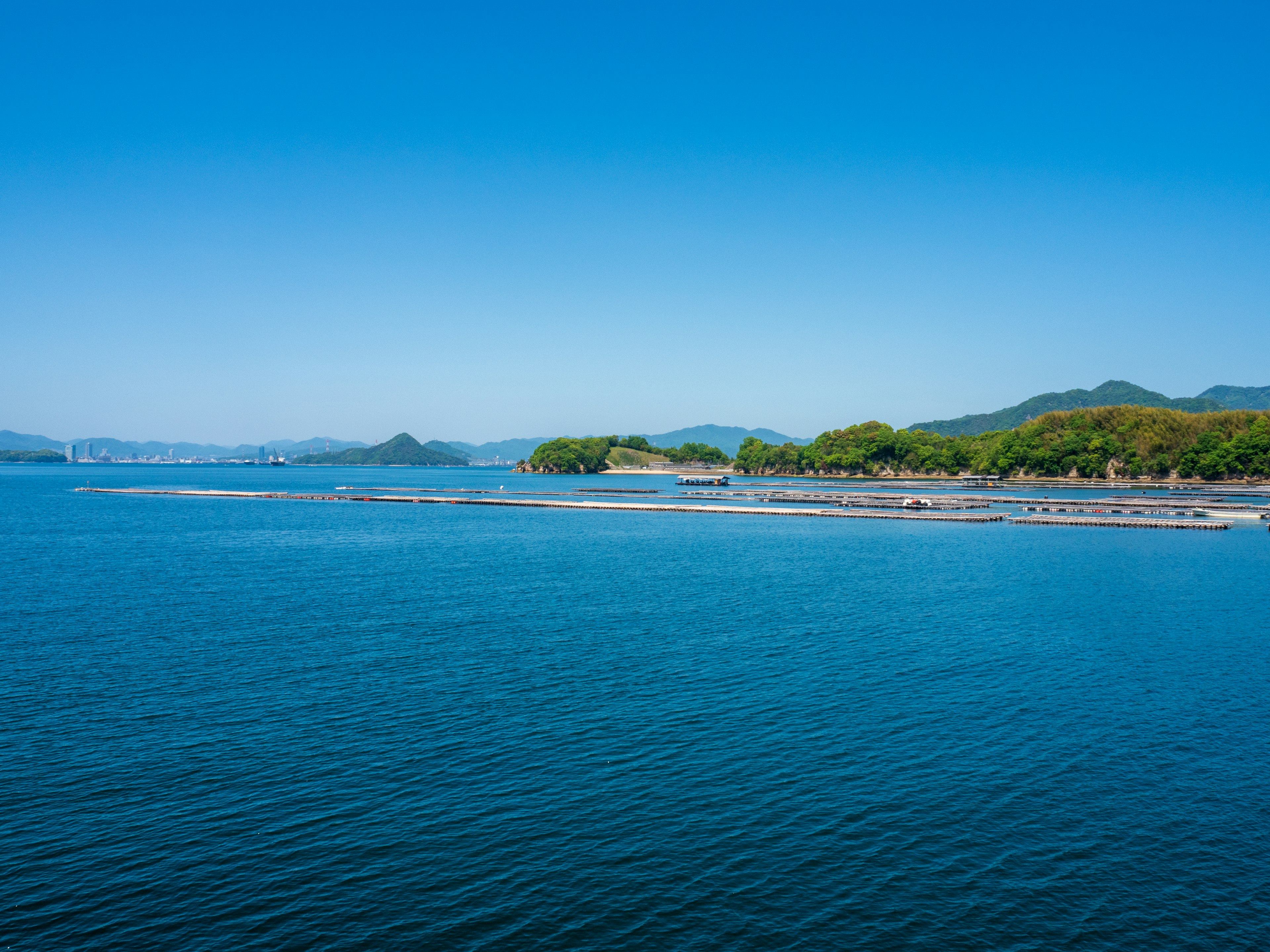 Vista panoramica del mare blu calmo sotto un cielo sereno con isole verdi