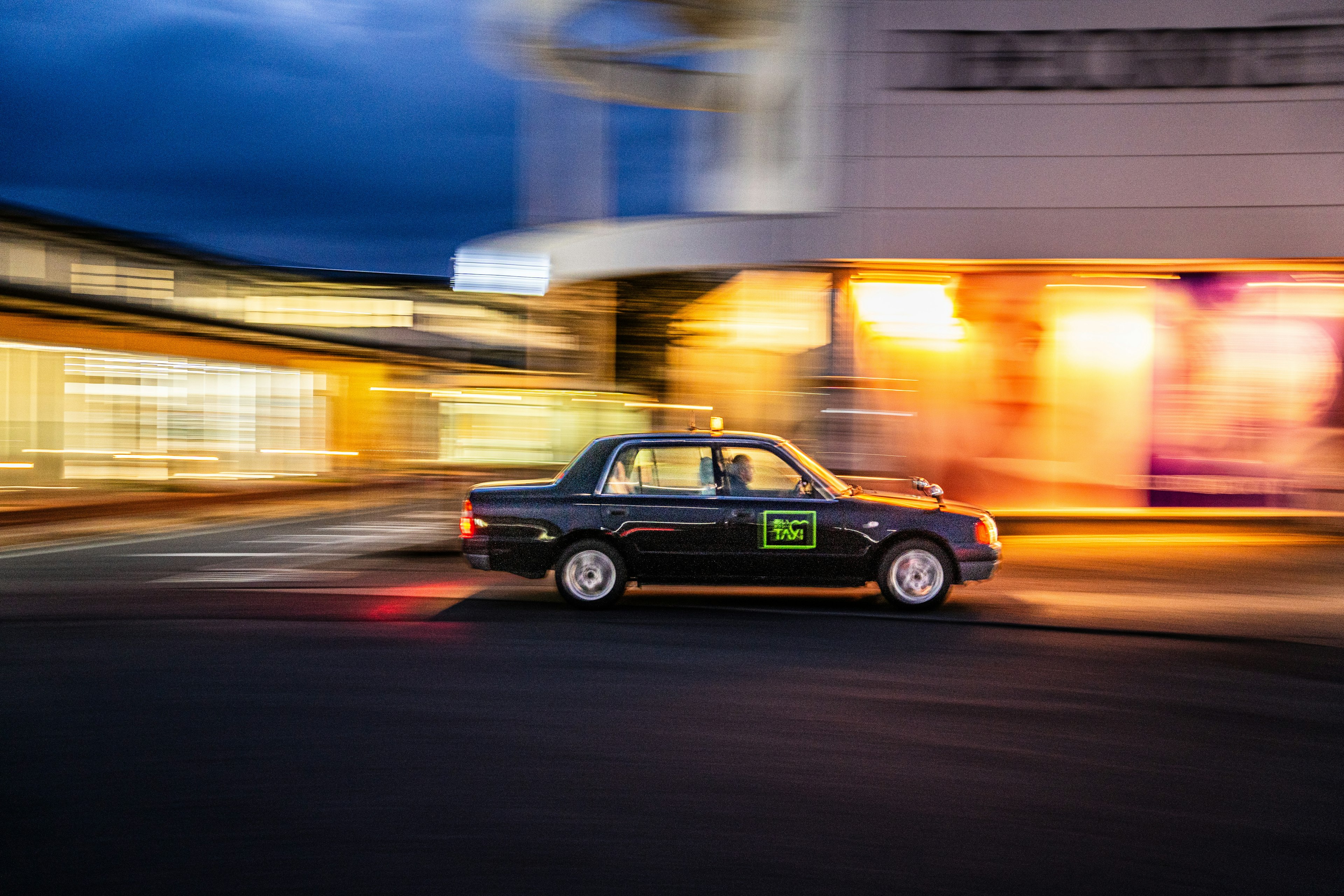 運転中のタクシーが夜の街を背景に走っている