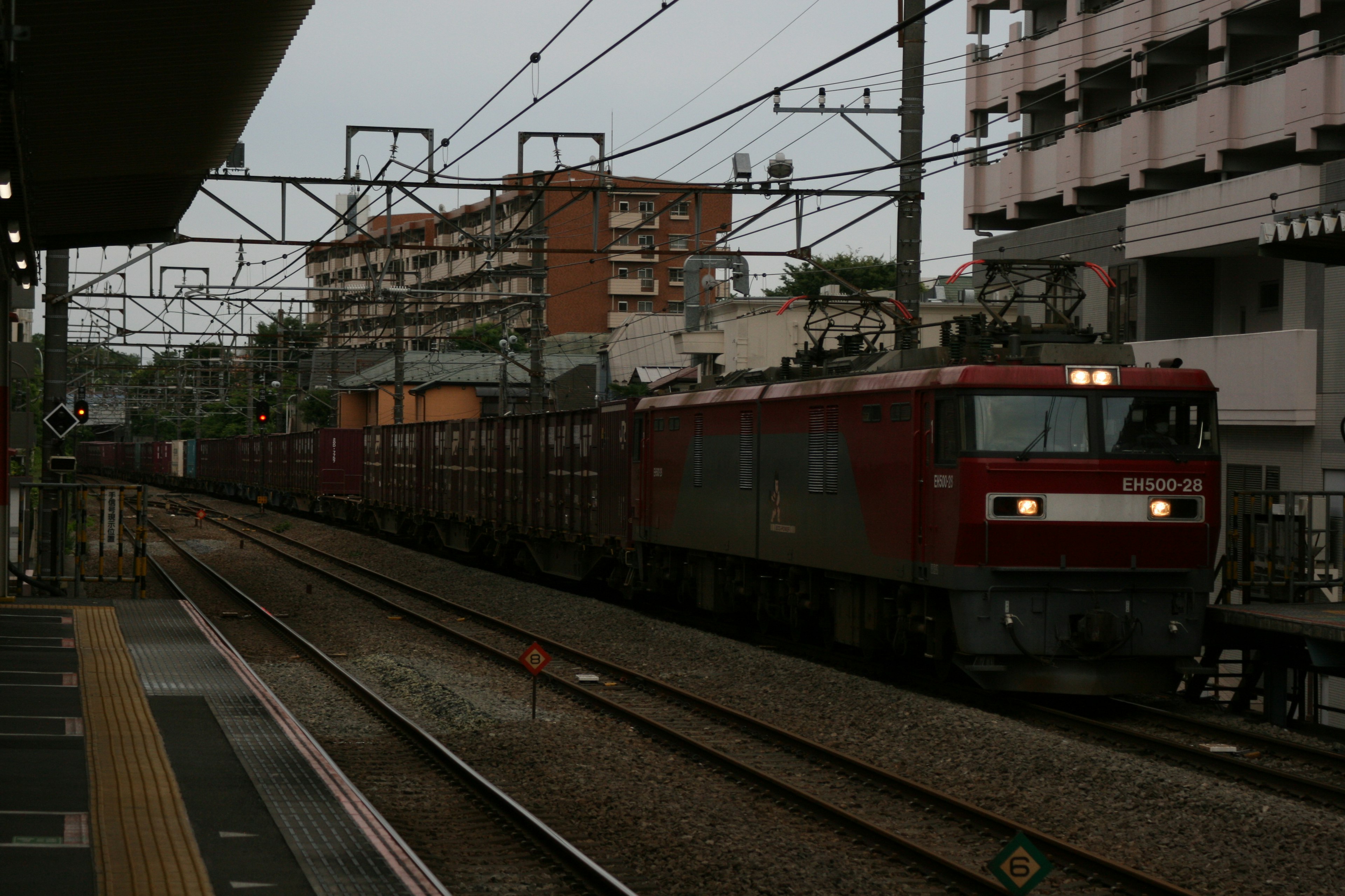 赤い貨物列車が駅に近づいている風景