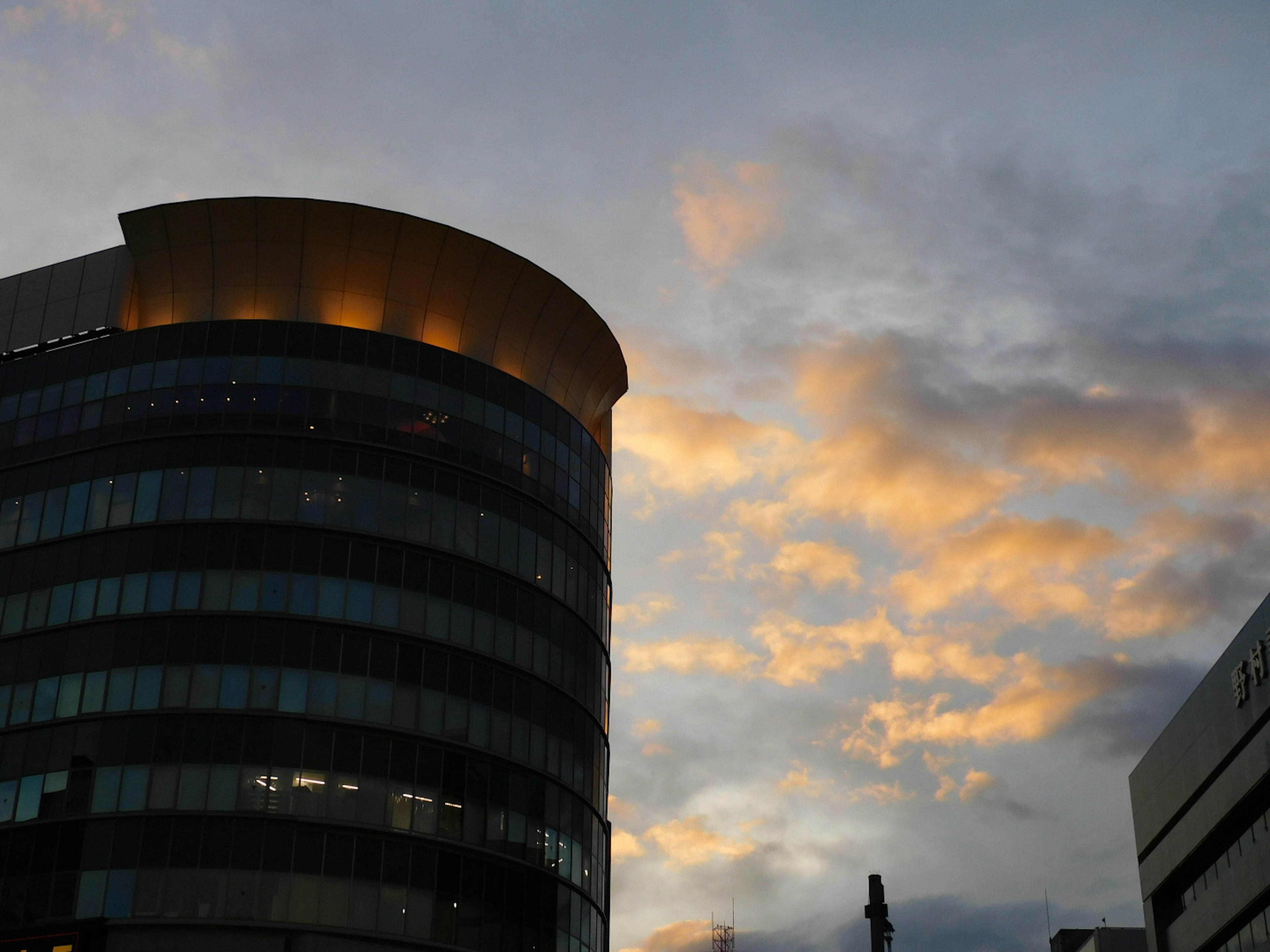 Fachada de un edificio moderno iluminada por el atardecer con cielo nublado