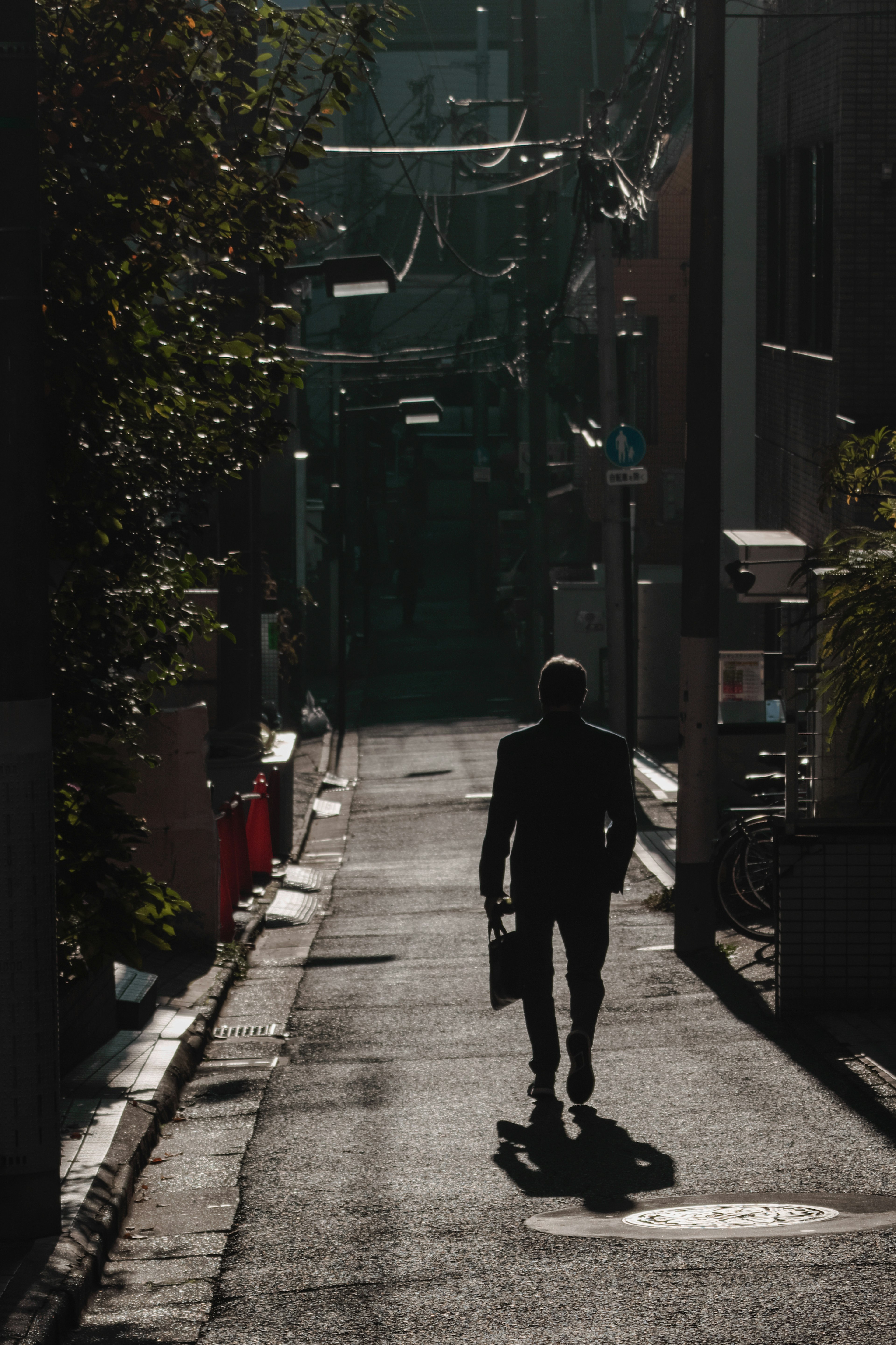 薄暗い路地を歩くビジネスマンのシルエット