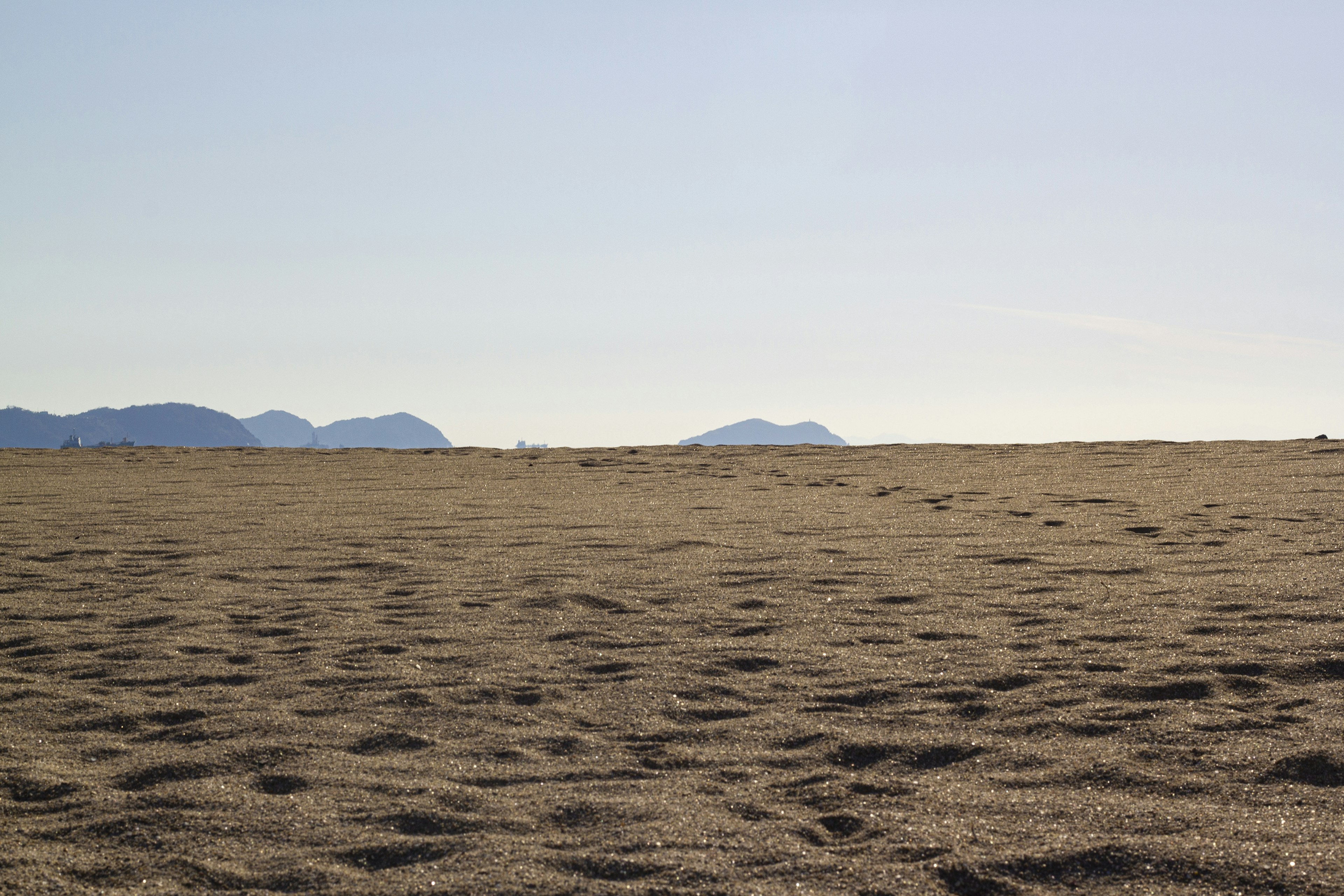 Weitläufiger Sandstrand mit fernen Bergen