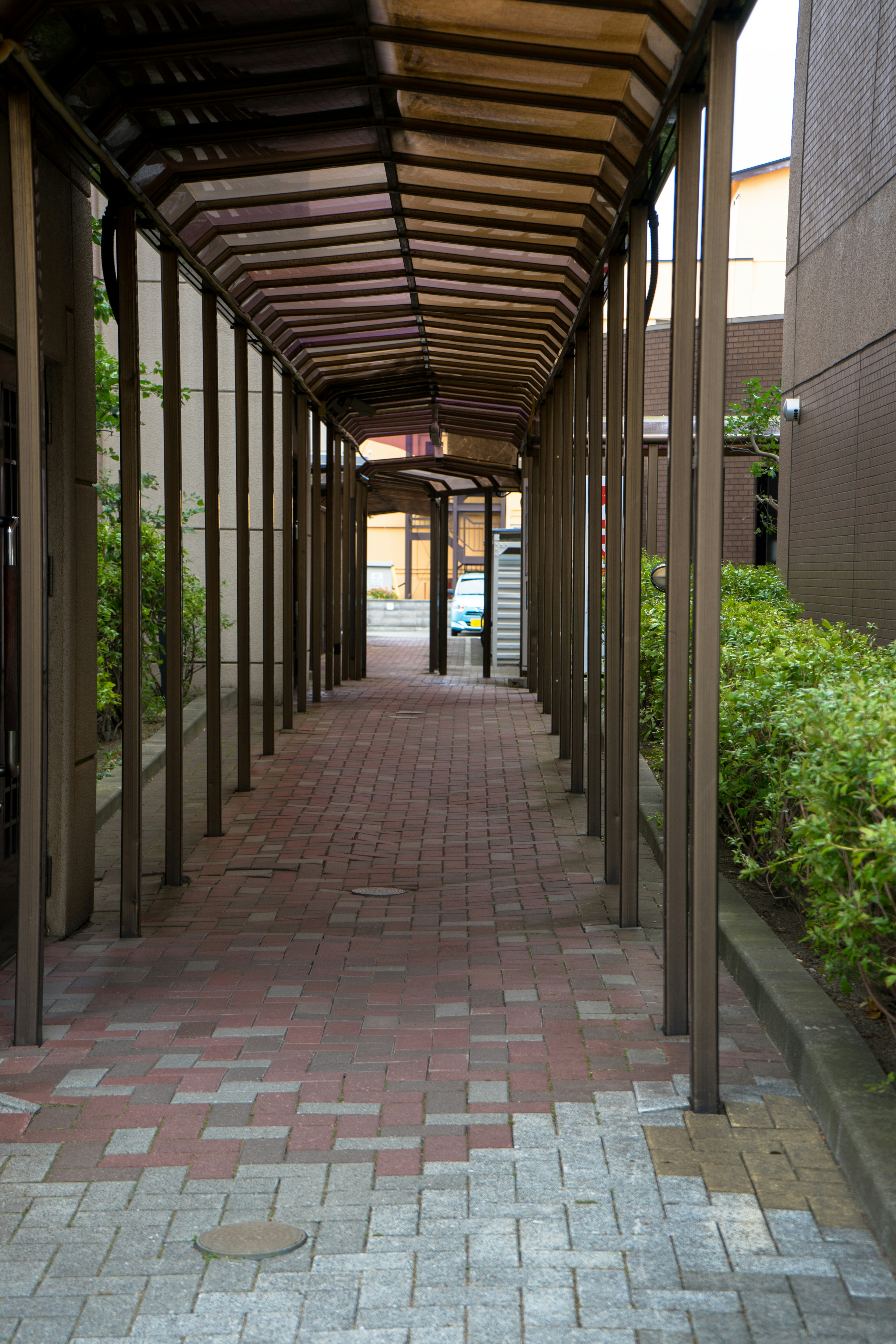 Narrow pathway with wooden arches and brick pavement features