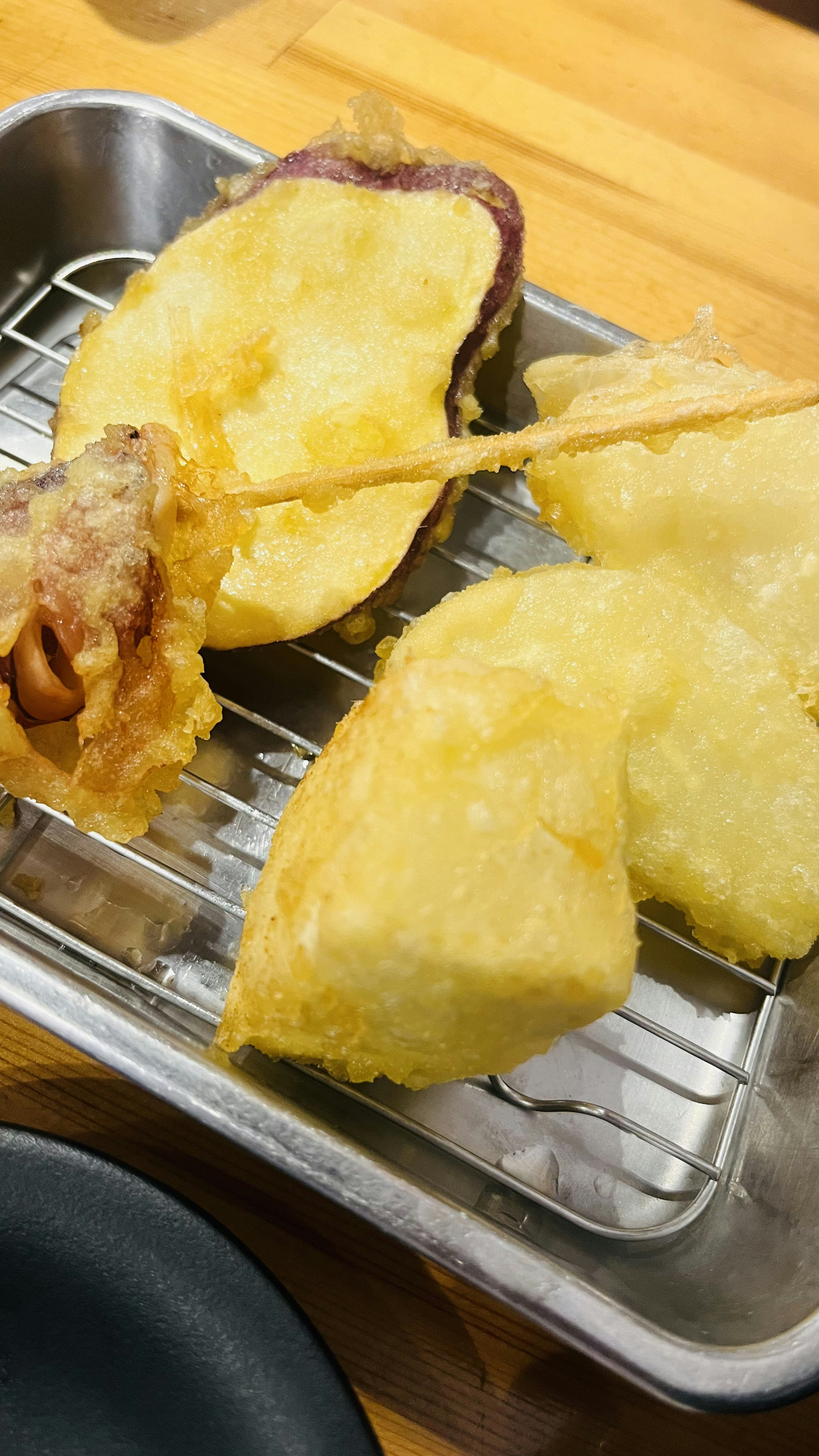 A tray of assorted fried foods including tempura and skewers