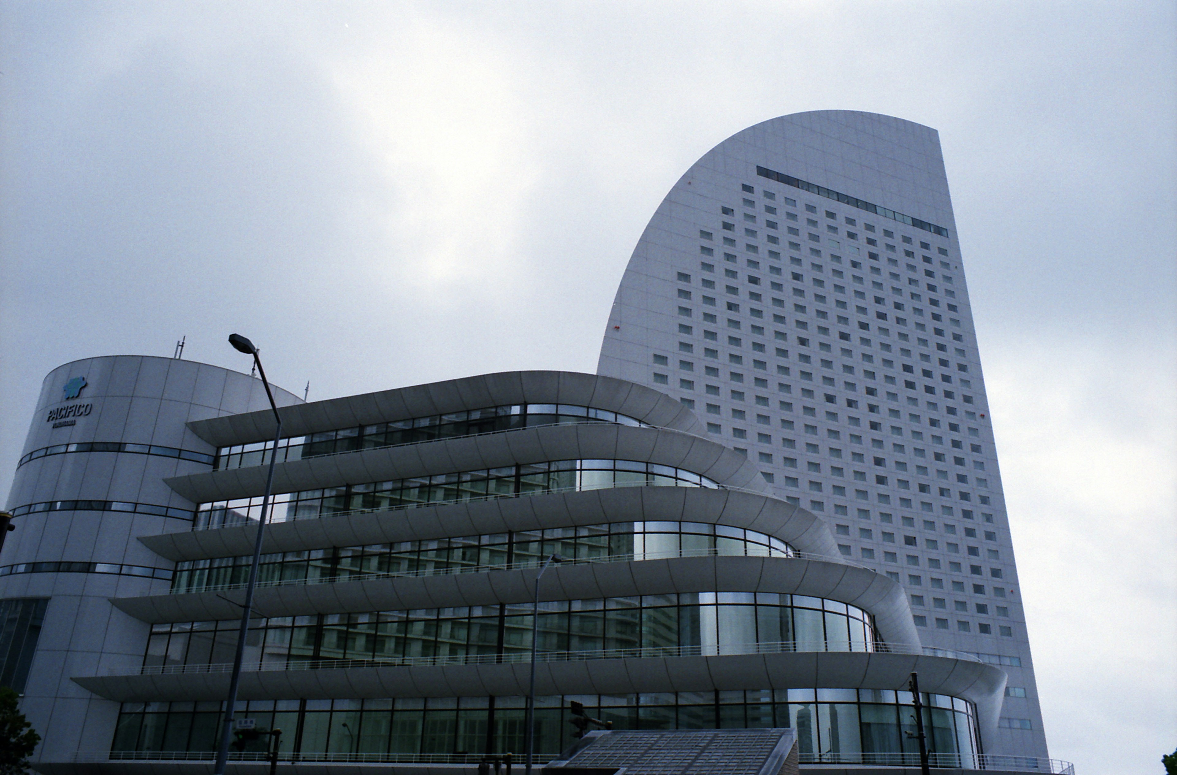 Exterior moderno de un edificio con diseño curvo fachada de vidrio y cielo nublado