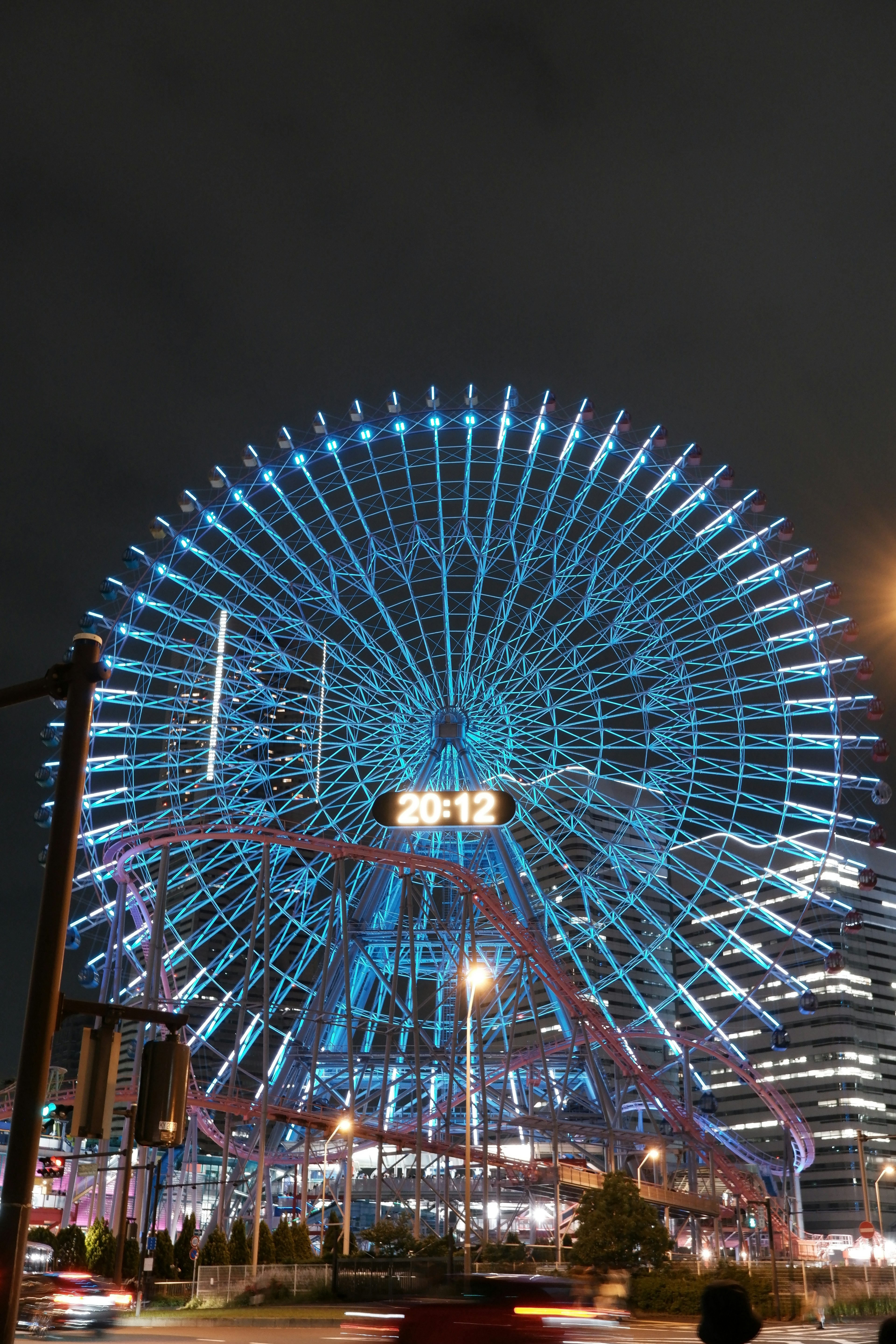 Grande roue illuminée de lumières bleues contre un ciel nocturne