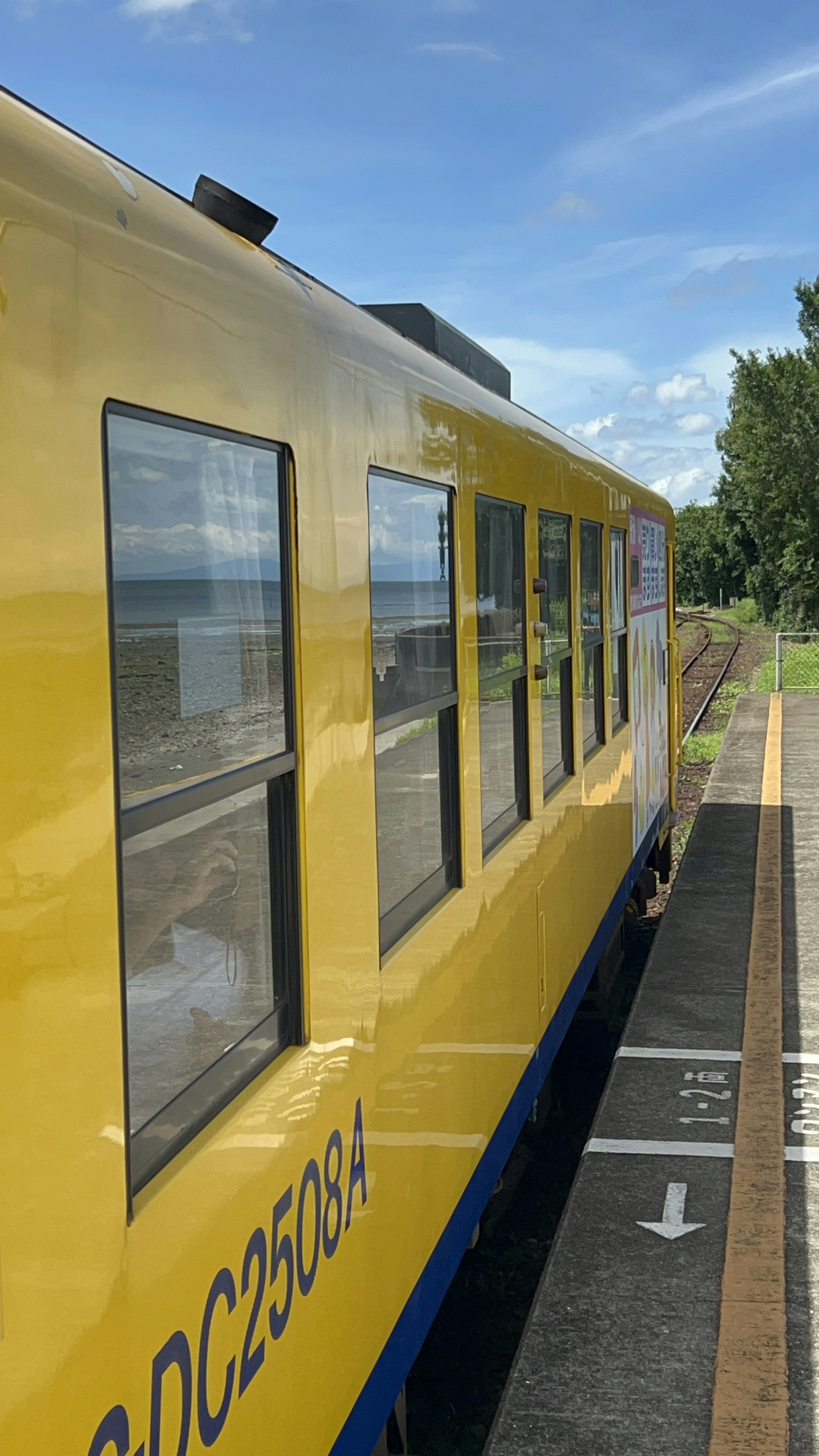 Train jaune à la gare avec des accents bleus et un ciel dégagé