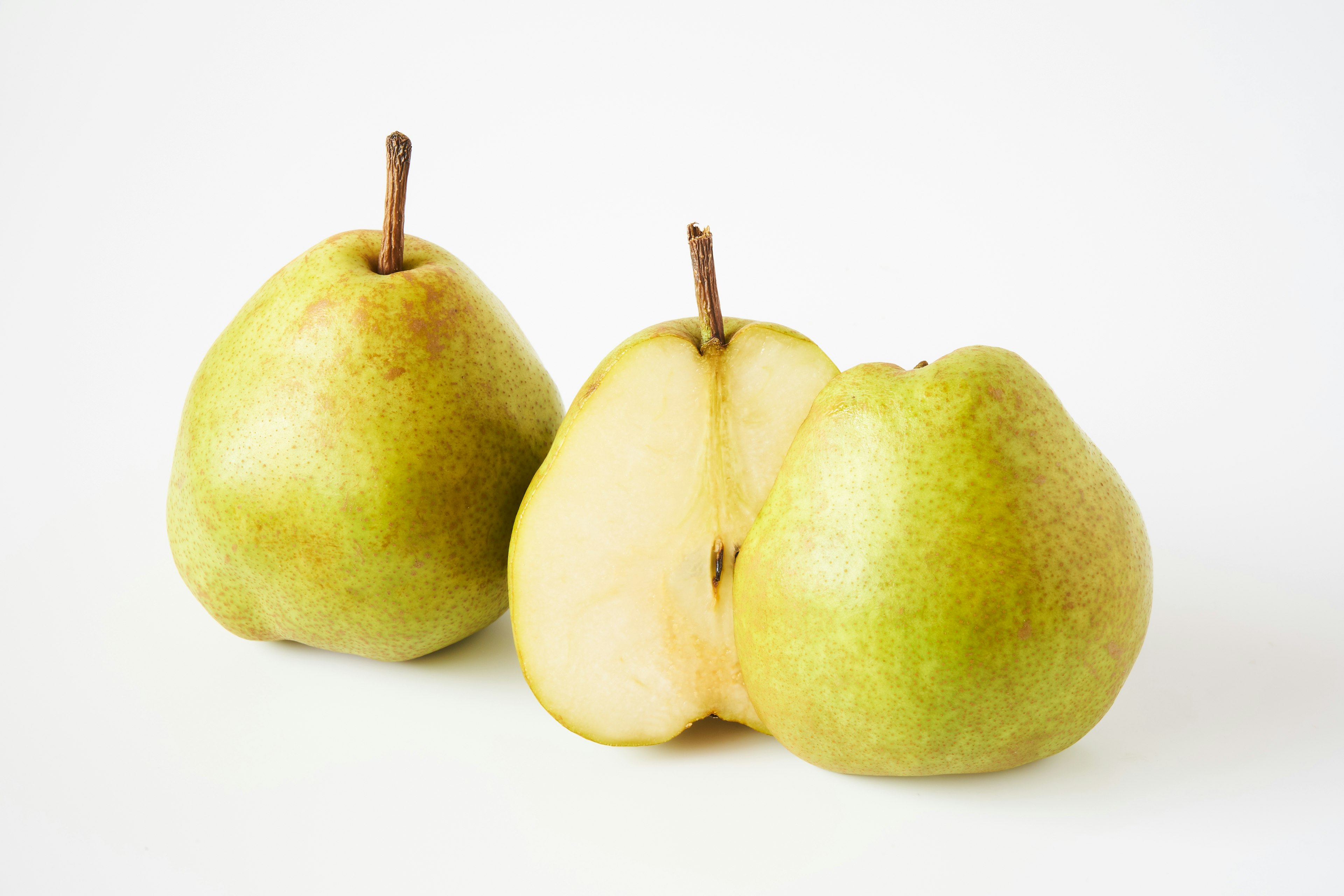 Two green pears with one pear sliced in half