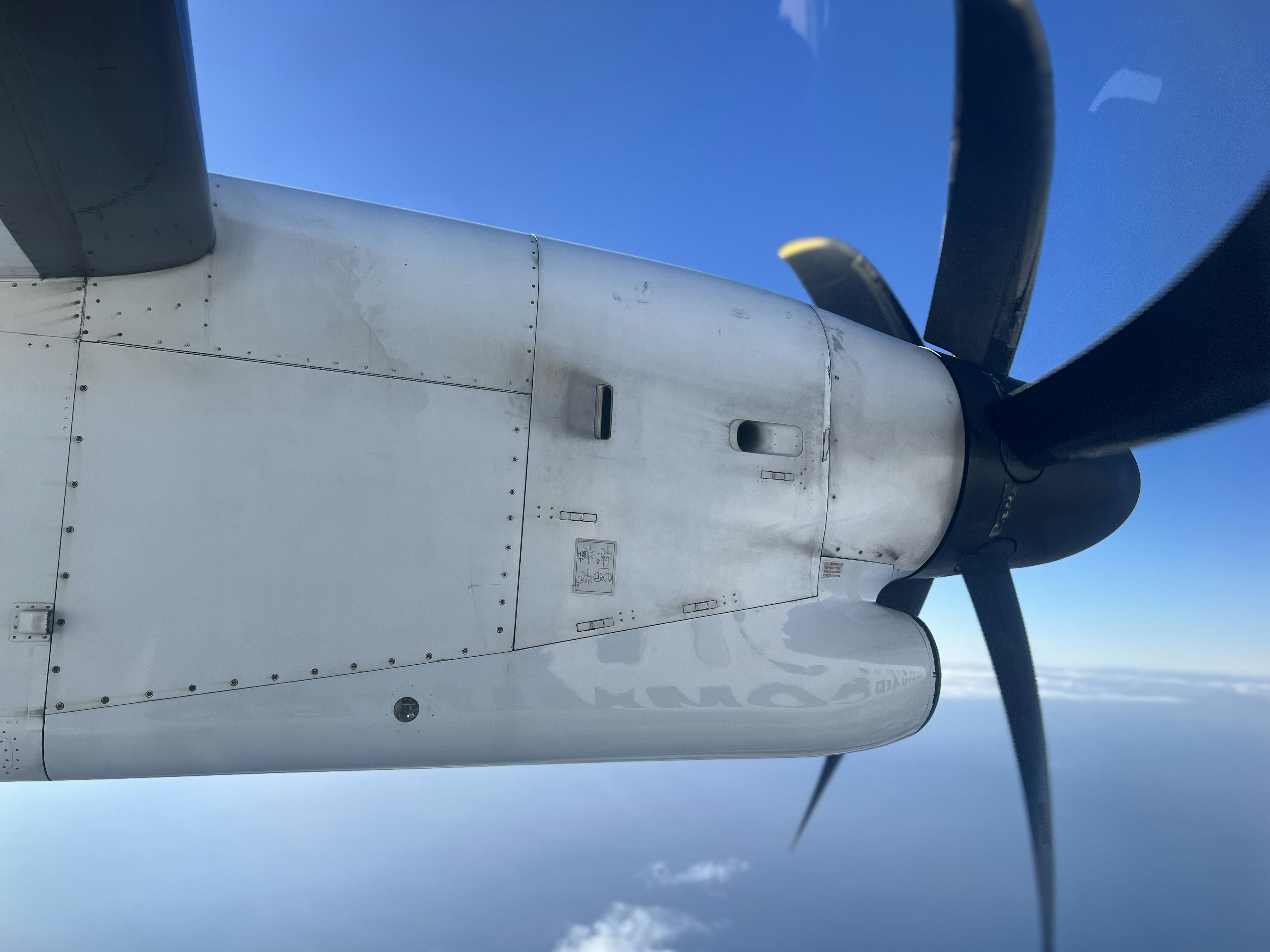 飛行機のプロペラと翼の一部が青い空を背景に見える