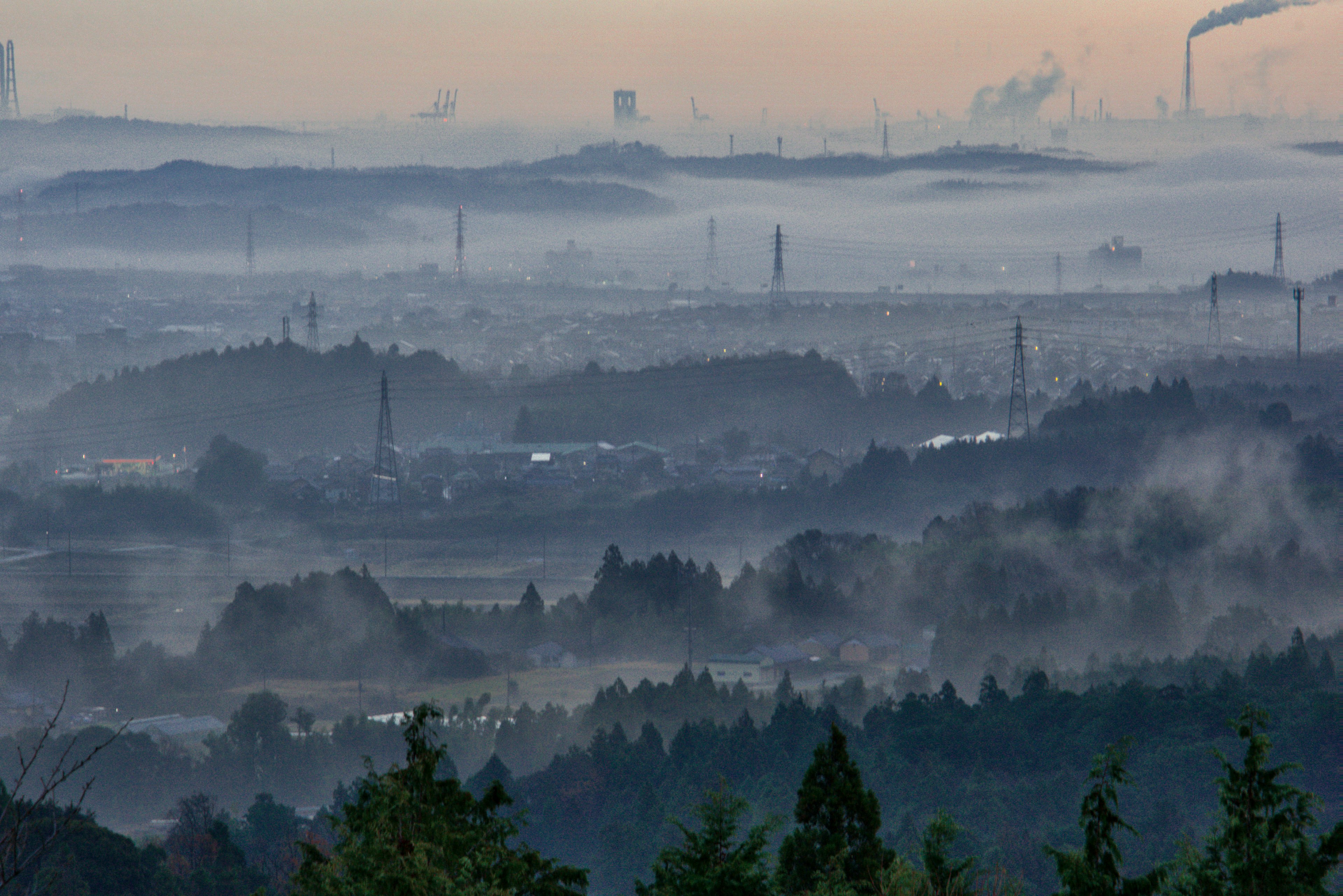 Paisaje industrial envuelto en niebla con montañas distantes