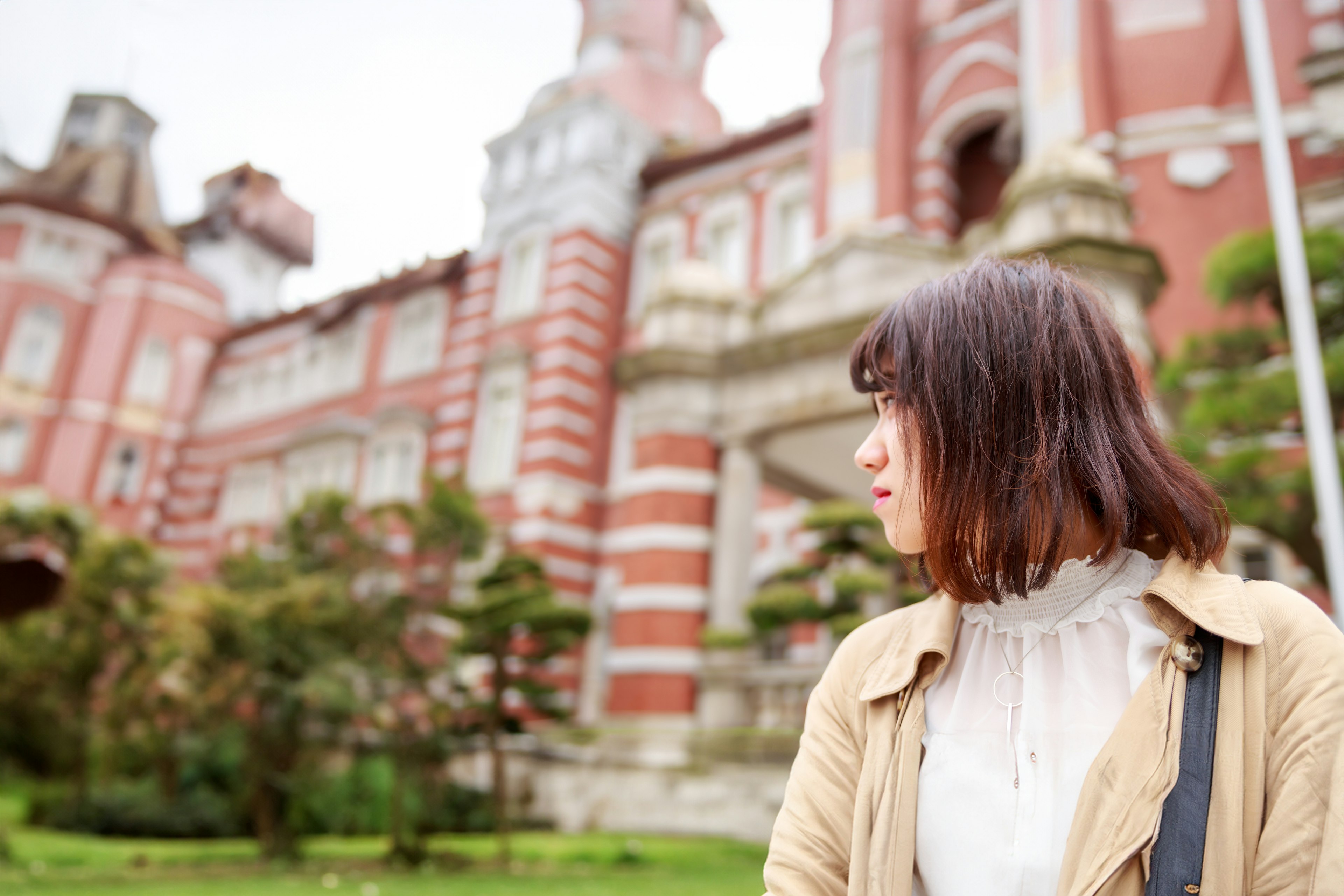 A woman looking away in front of a beautiful red building