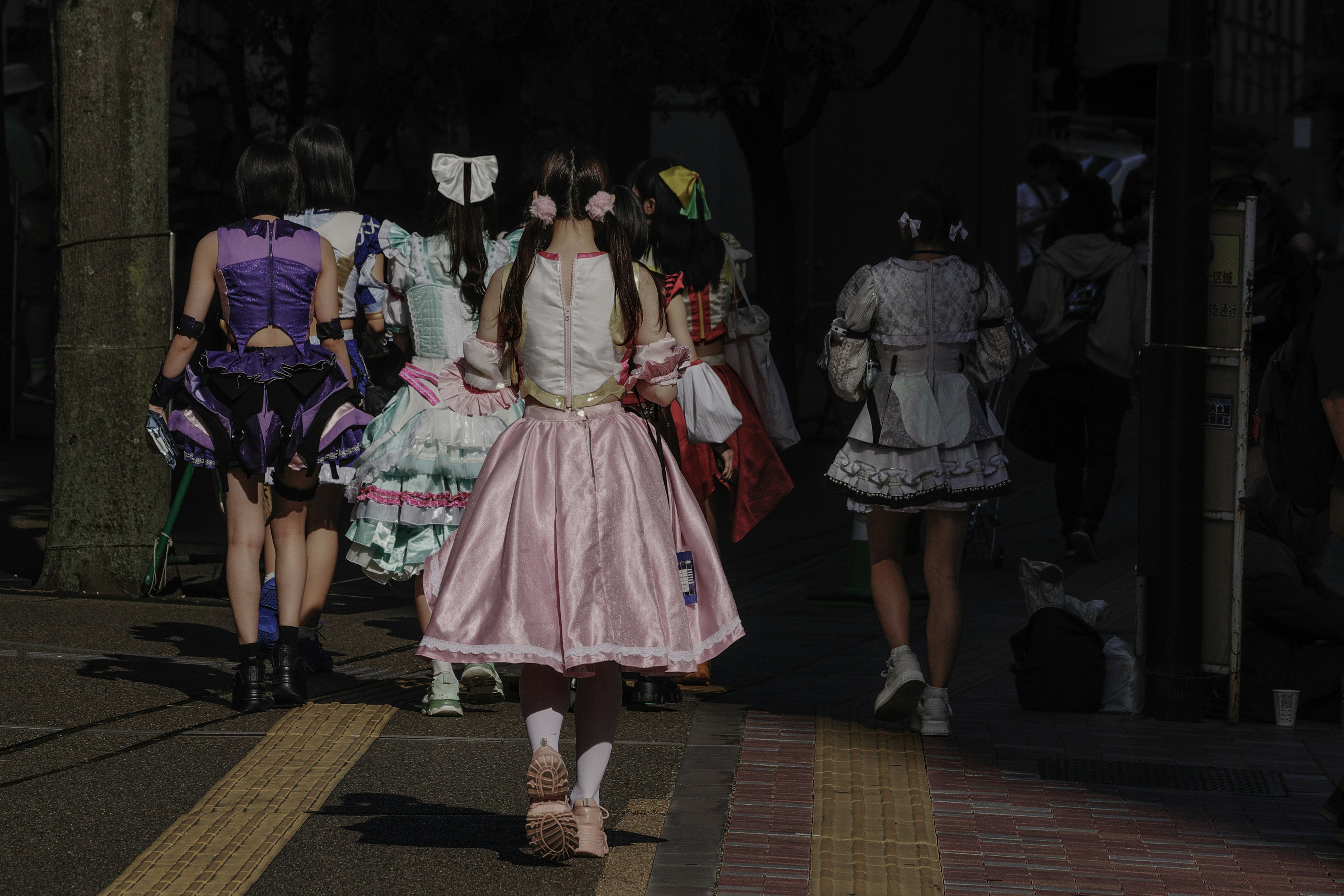 Groupe de cosplayers marchant dans des costumes colorés dans une rue faiblement éclairée