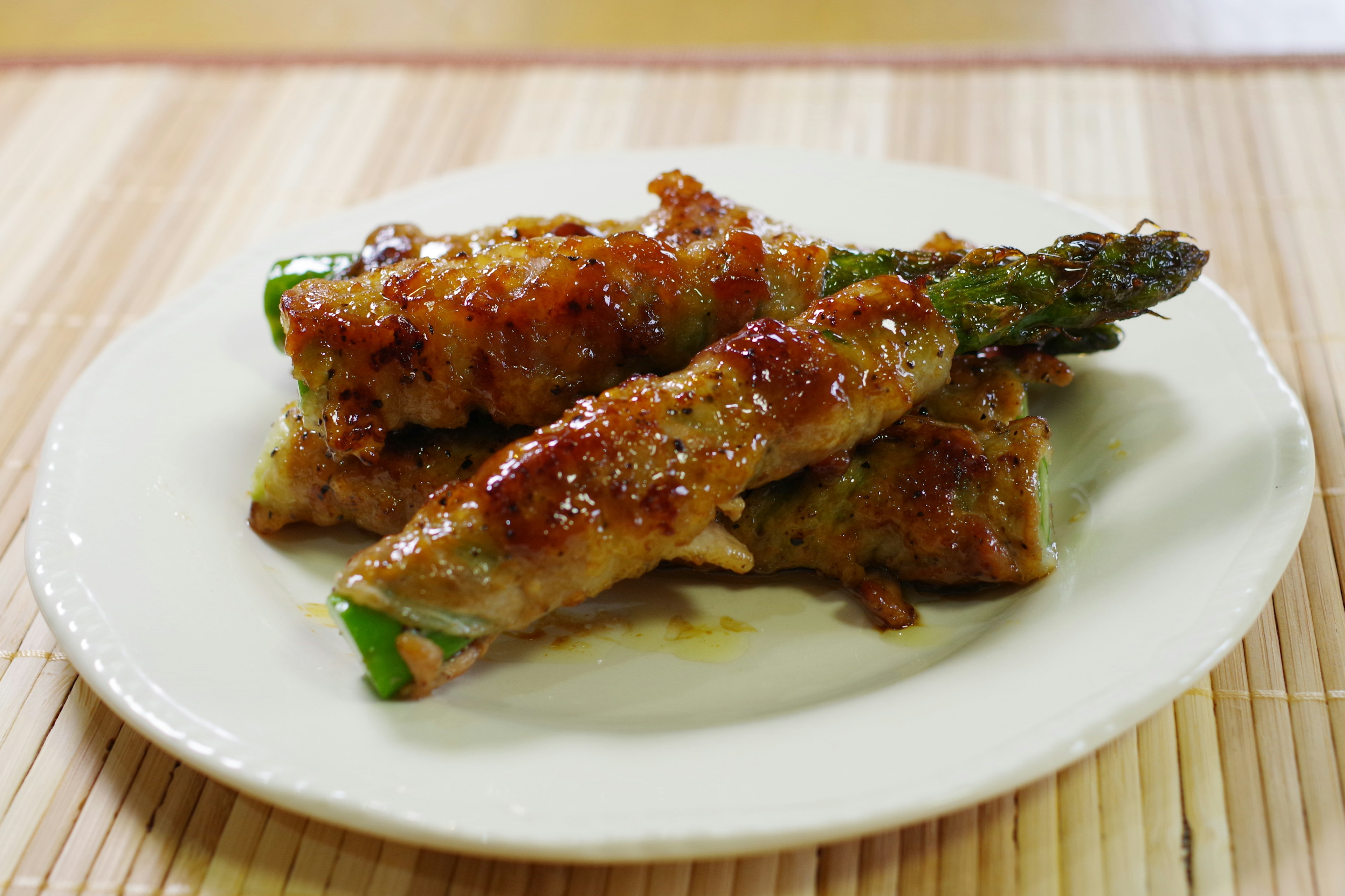 Piring daging yang dibungkus asparagus dengan saus