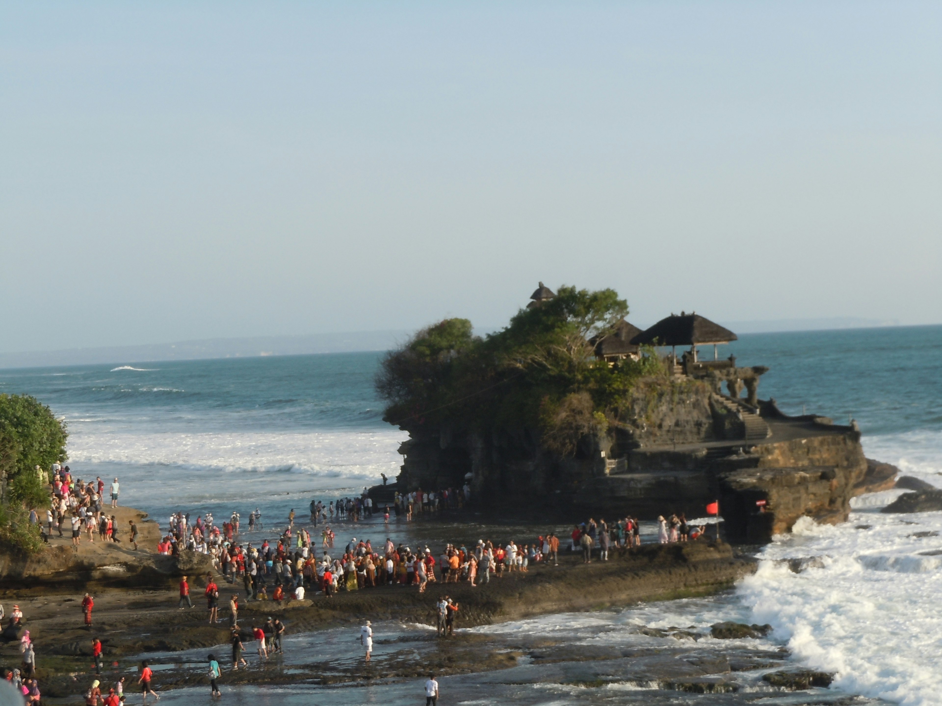 Rassemblement de personnes au temple de Tanah Lot à Bali avec des vagues océaniques