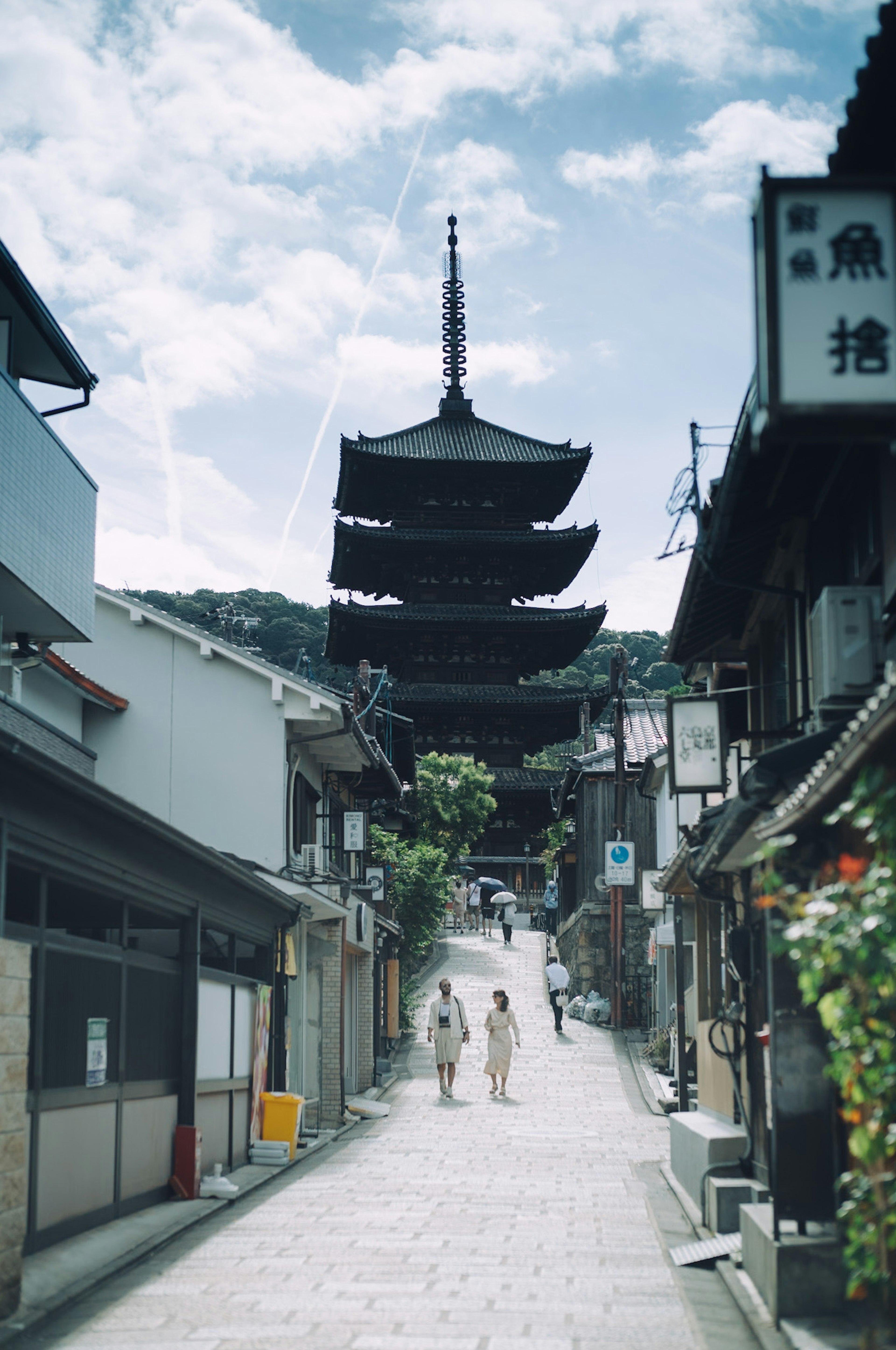 Zwei Personen in Kimonos, die in einer historischen Straße mit einer Pagode in Kyoto spazieren