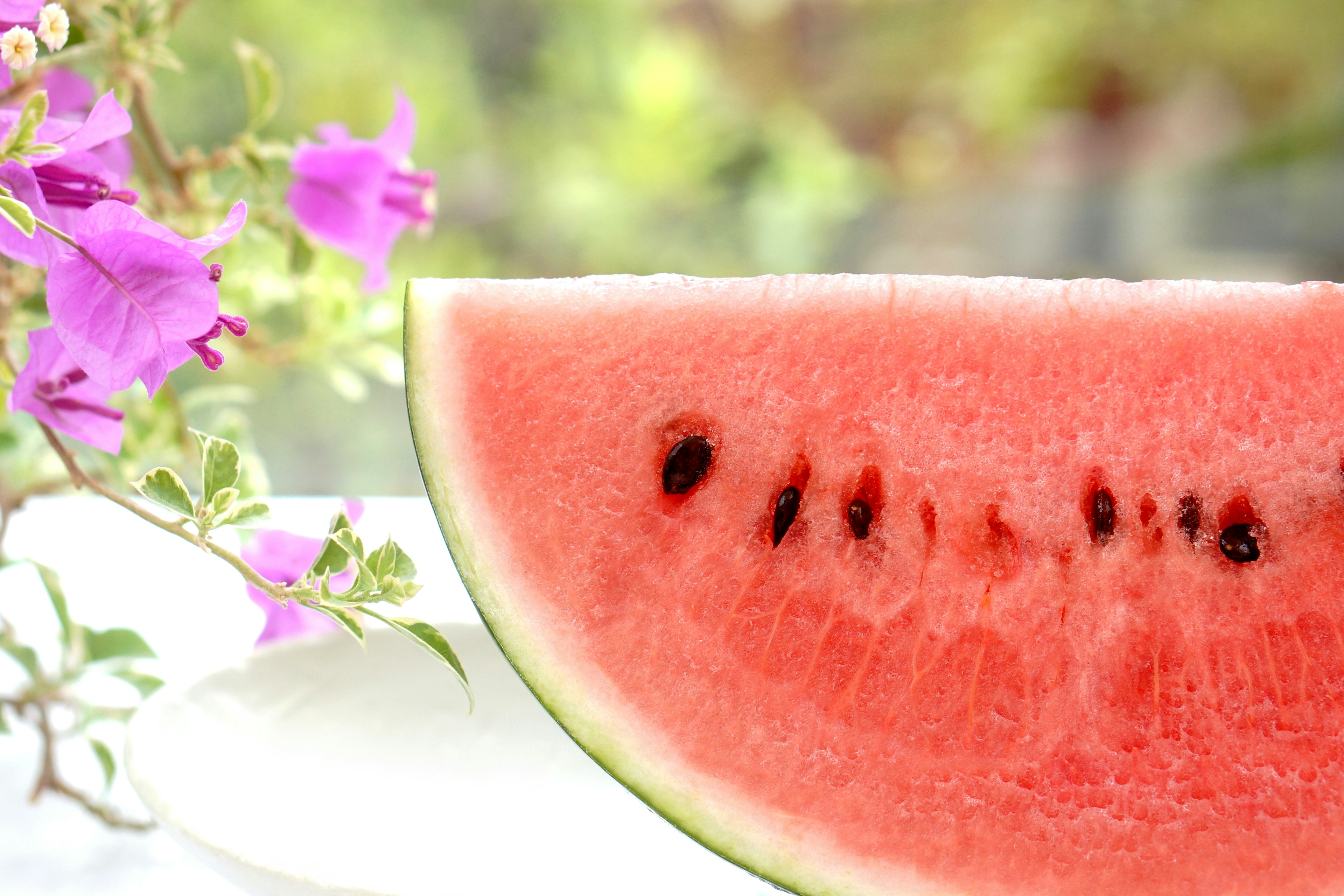 A slice of watermelon next to pink flowers